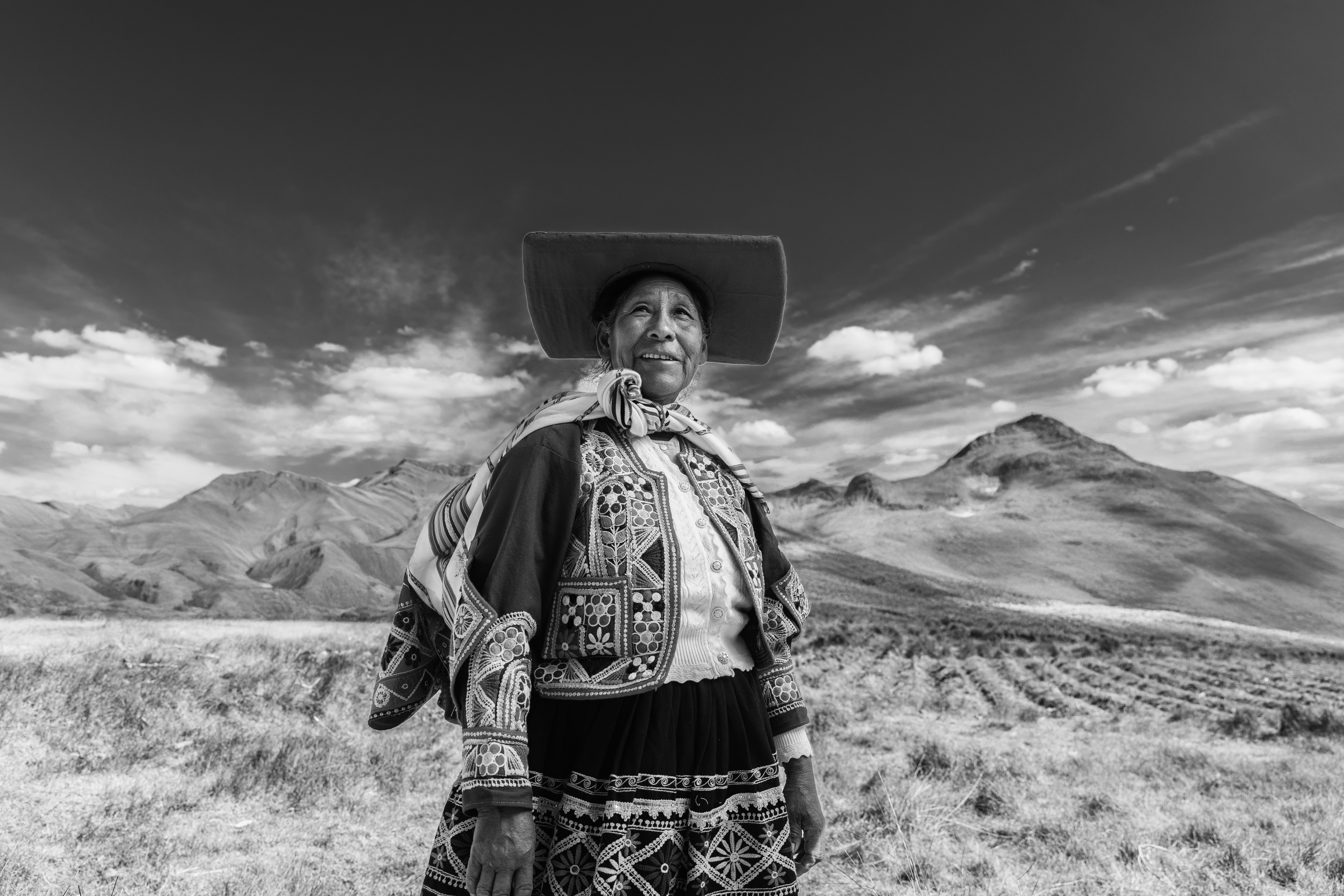 Elderly woman in traditional clothing with mountains behind