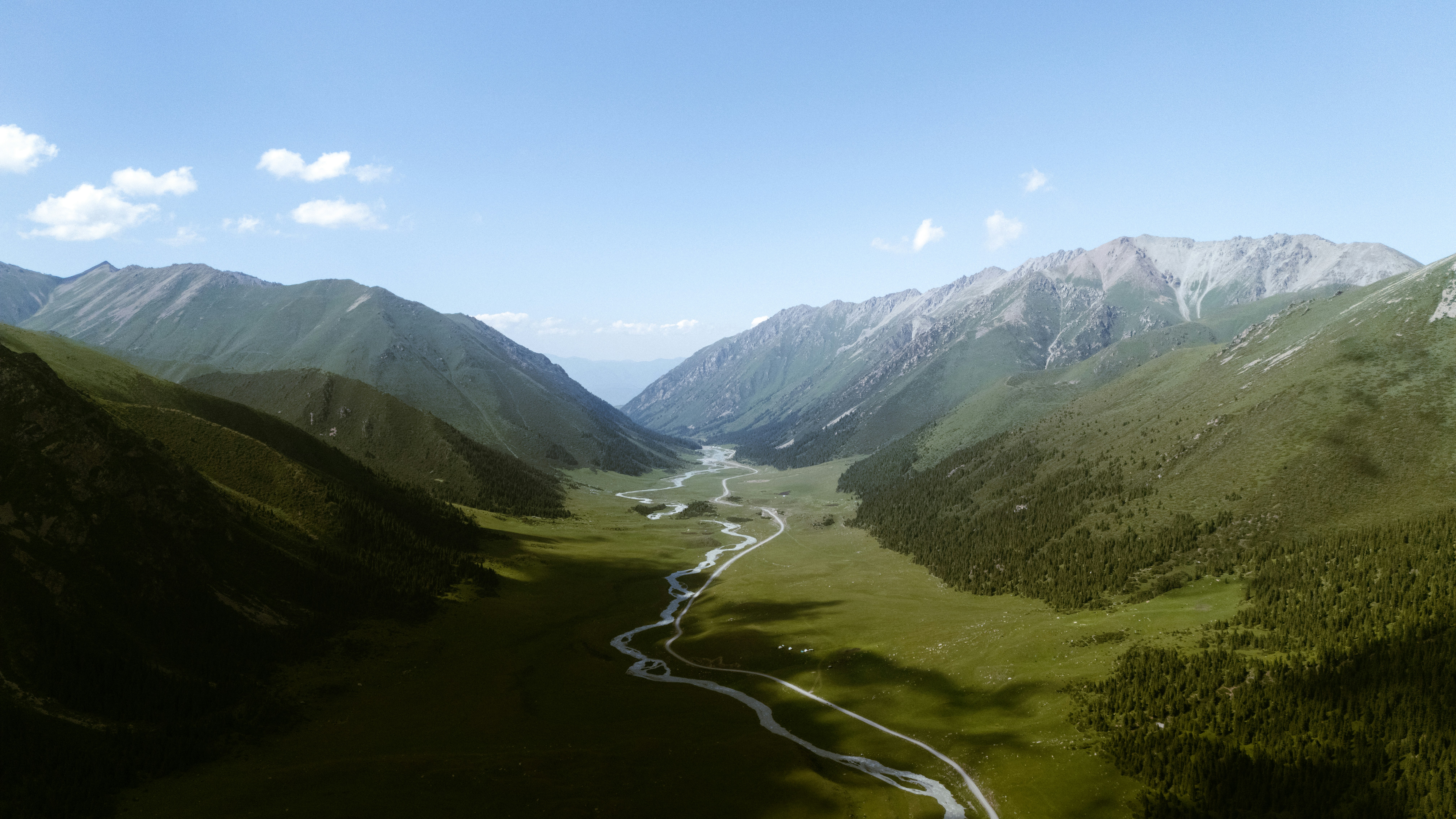 A winding river flows through a green mountain valley.