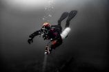 Scuba diver exploring dark underwater depths with bubbles.