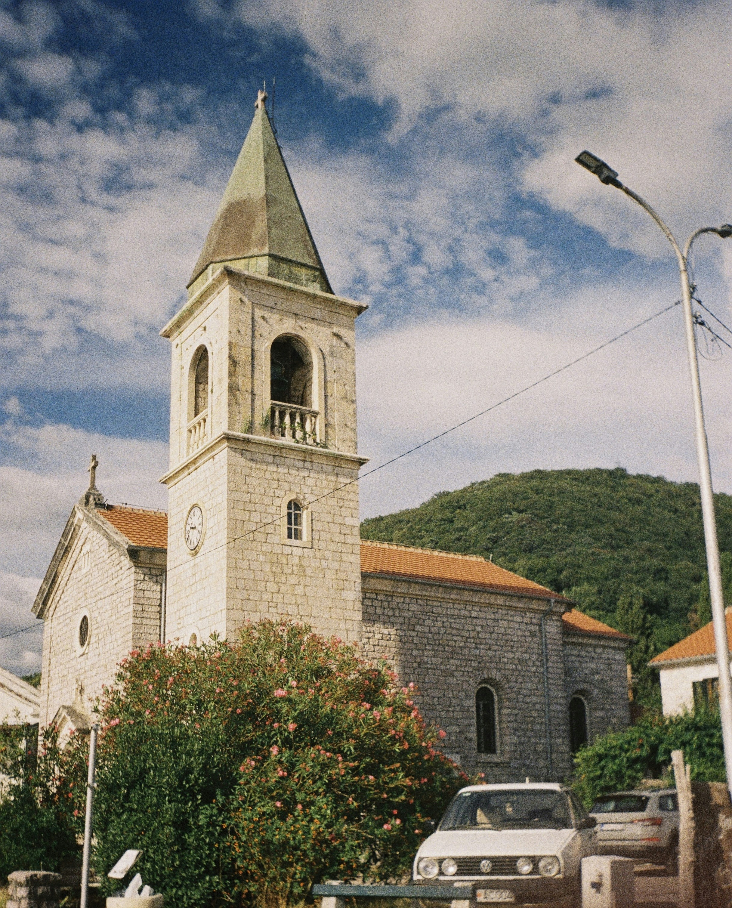 Stone church with a steeple and orange roof