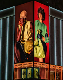 Two women modeling fashion on a building facade.