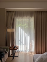 Sunlight streams through sheer curtains in a hotel room.