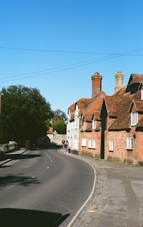 Curving road leads to quaint brick houses under blue sky.