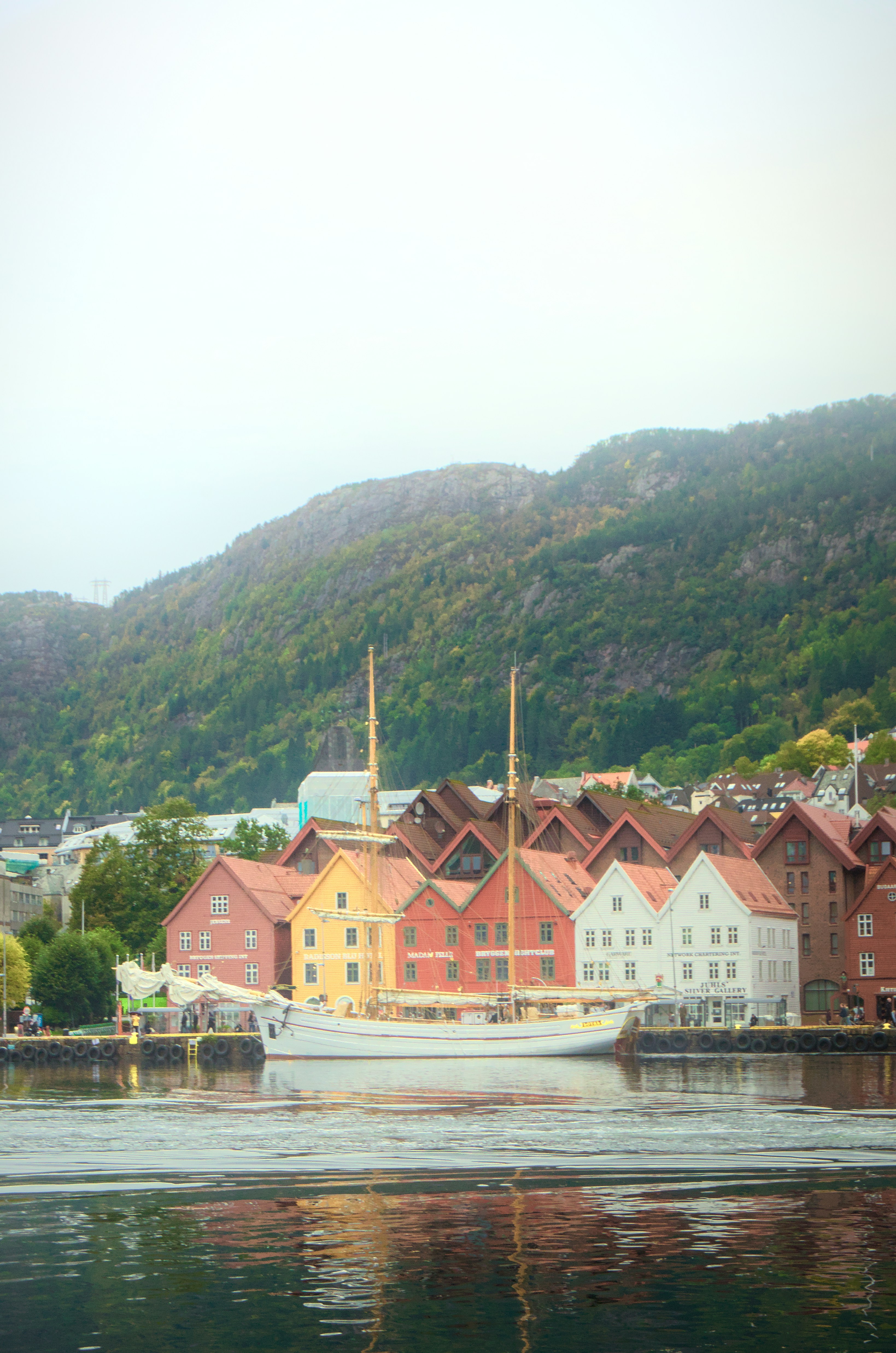 Bunte Gebäude säumen einen Hafen mit einem Segelboot.