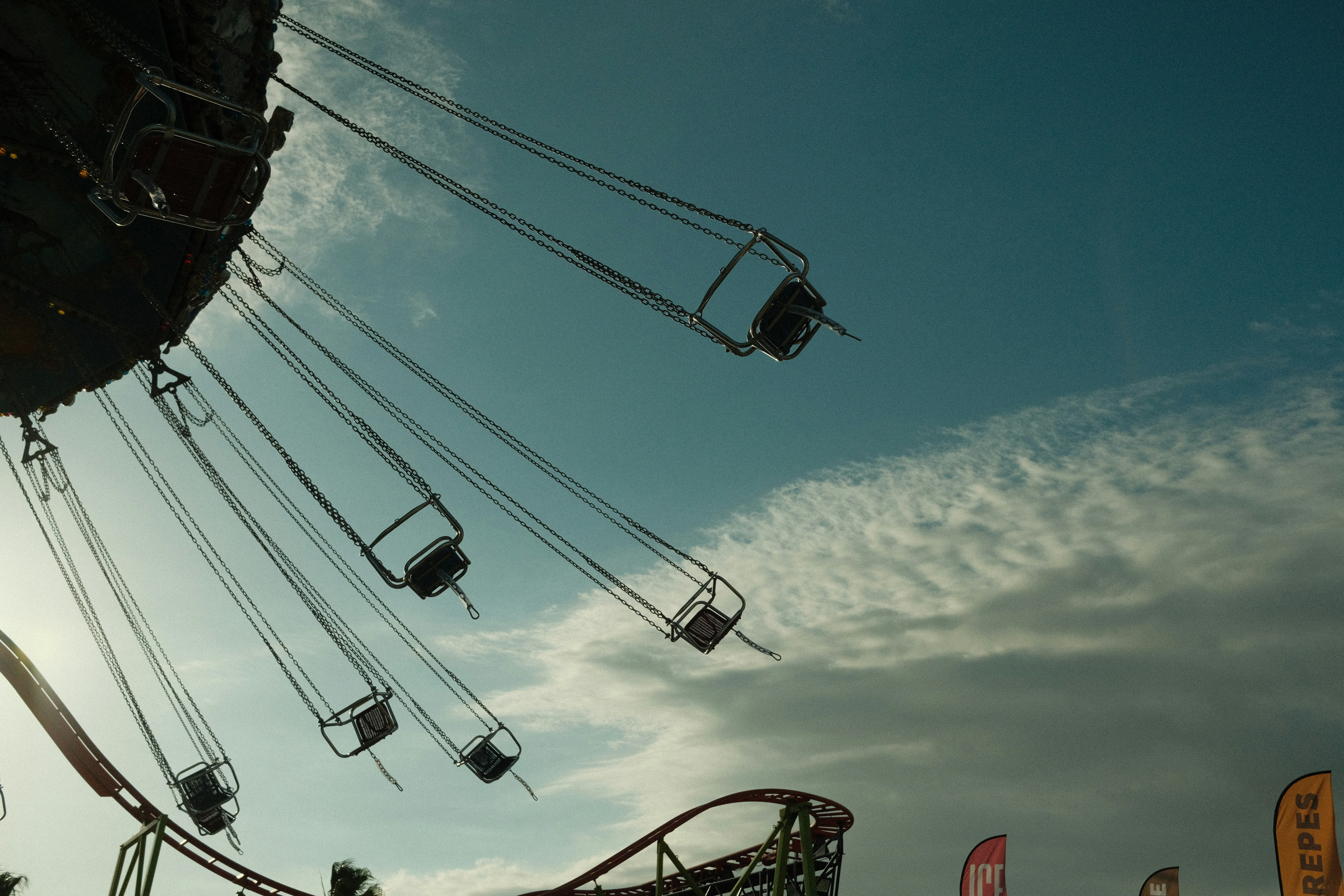 Swing ride at amusement park against cloudy sky