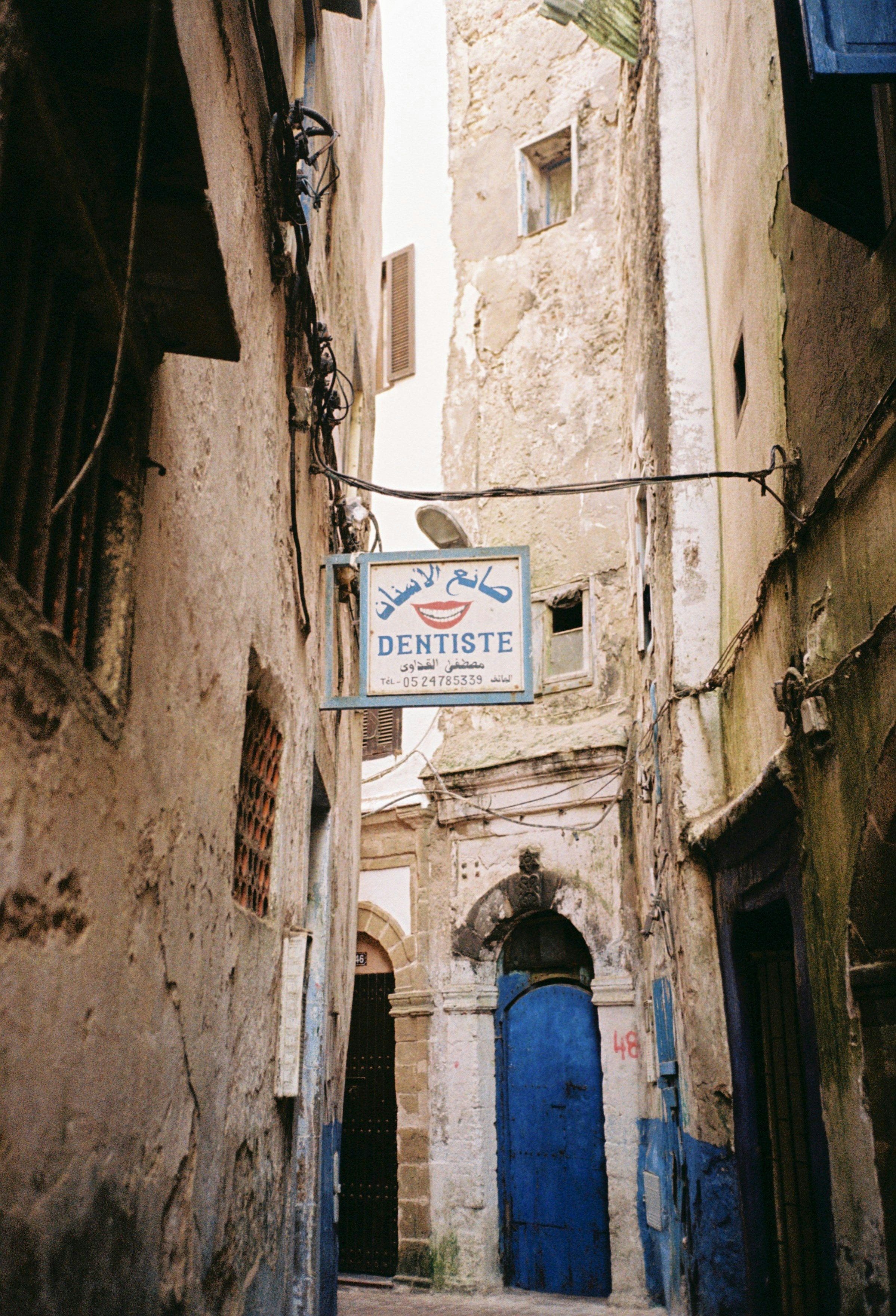 Narrow alleyway with weathered buildings and blue door.