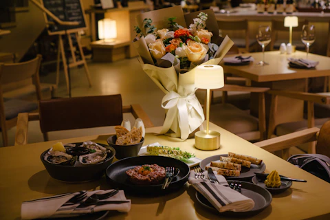 A table setting with food, flowers, and a lamp