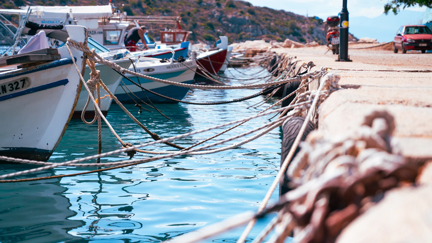 Fishing boats moored along a sunny harbor quay, representing the choice of the right specialist fishing boat accident attorney