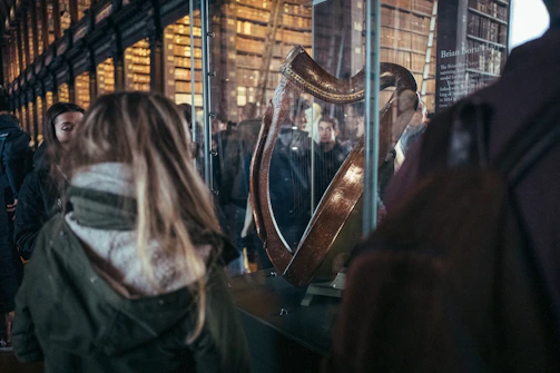 People viewing an ornate harp in a library exhibit