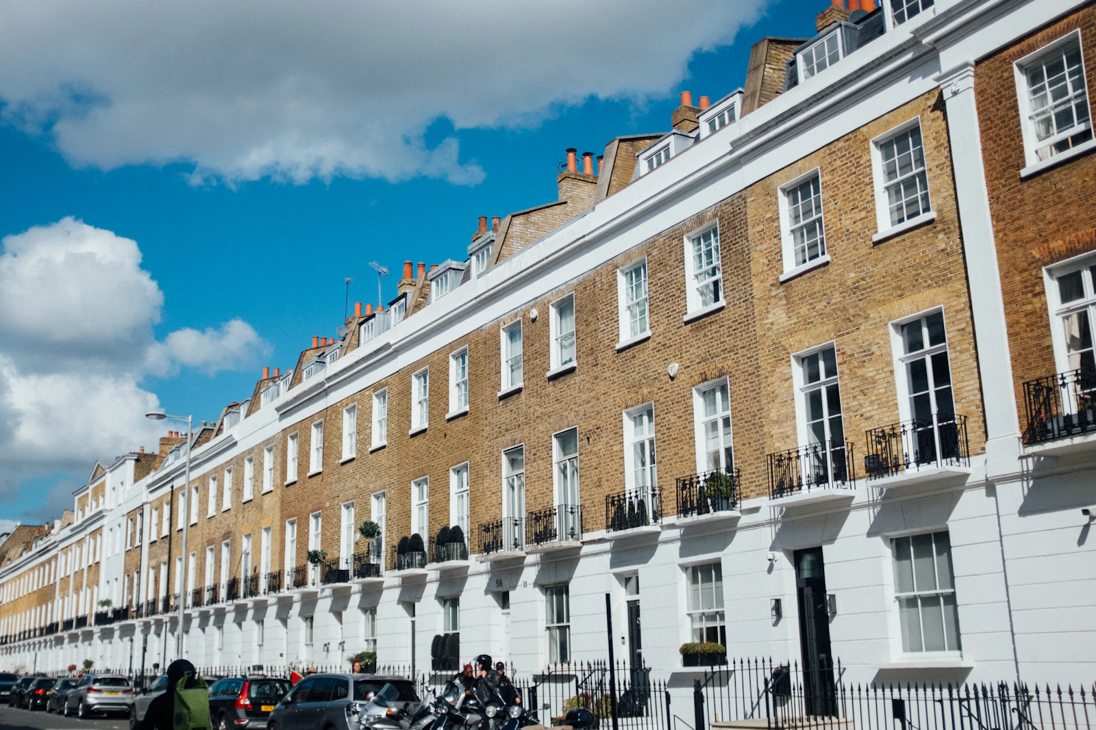 A row of traditional British terraced houses under a blue sky