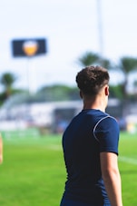 Young man on a soccer field with stadium in background.