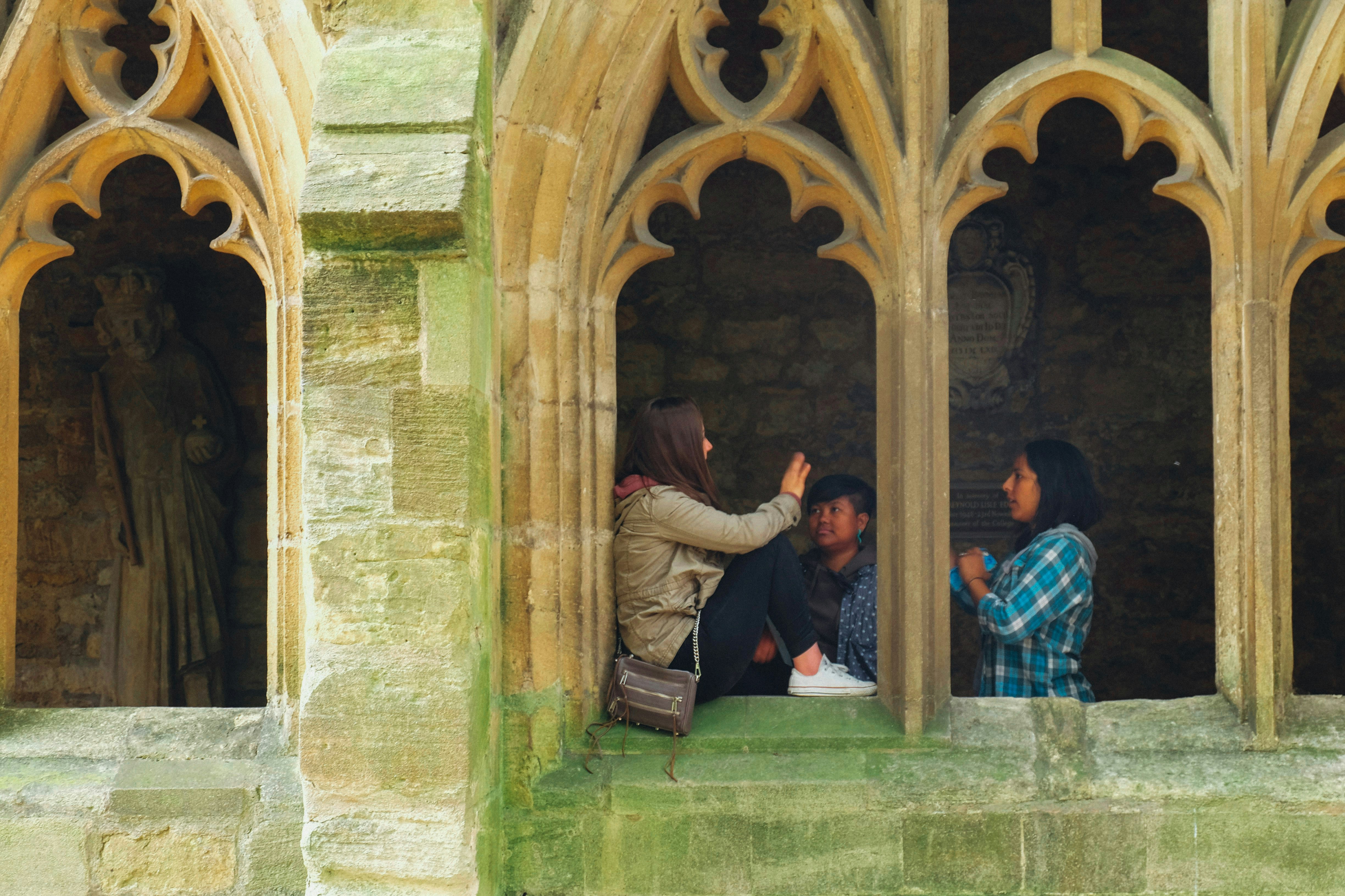 Three people sitting in arched stone windows
