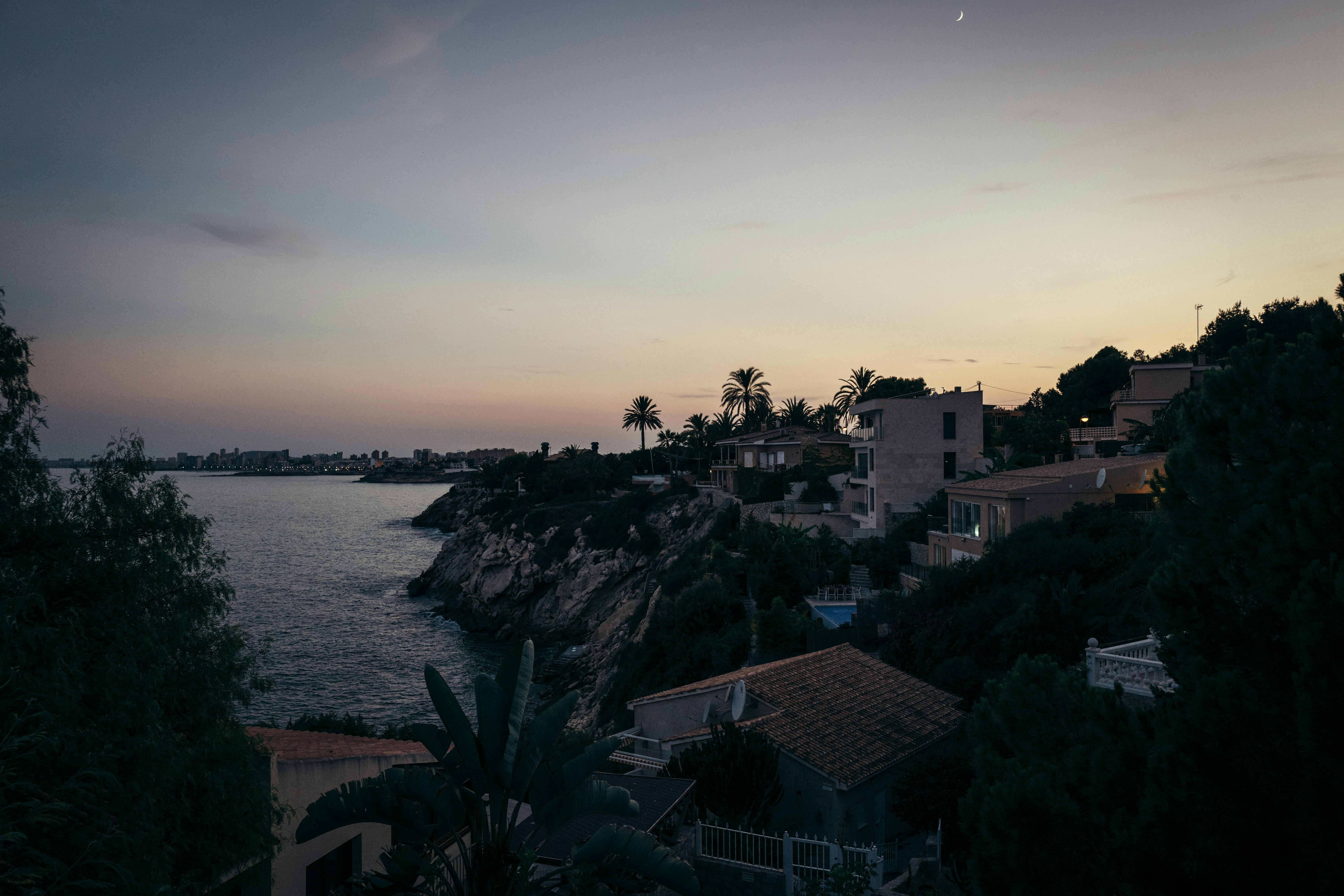 Coastal town buildings on a hill at dusk.