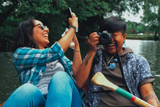 Two friends taking photos while riding a boat