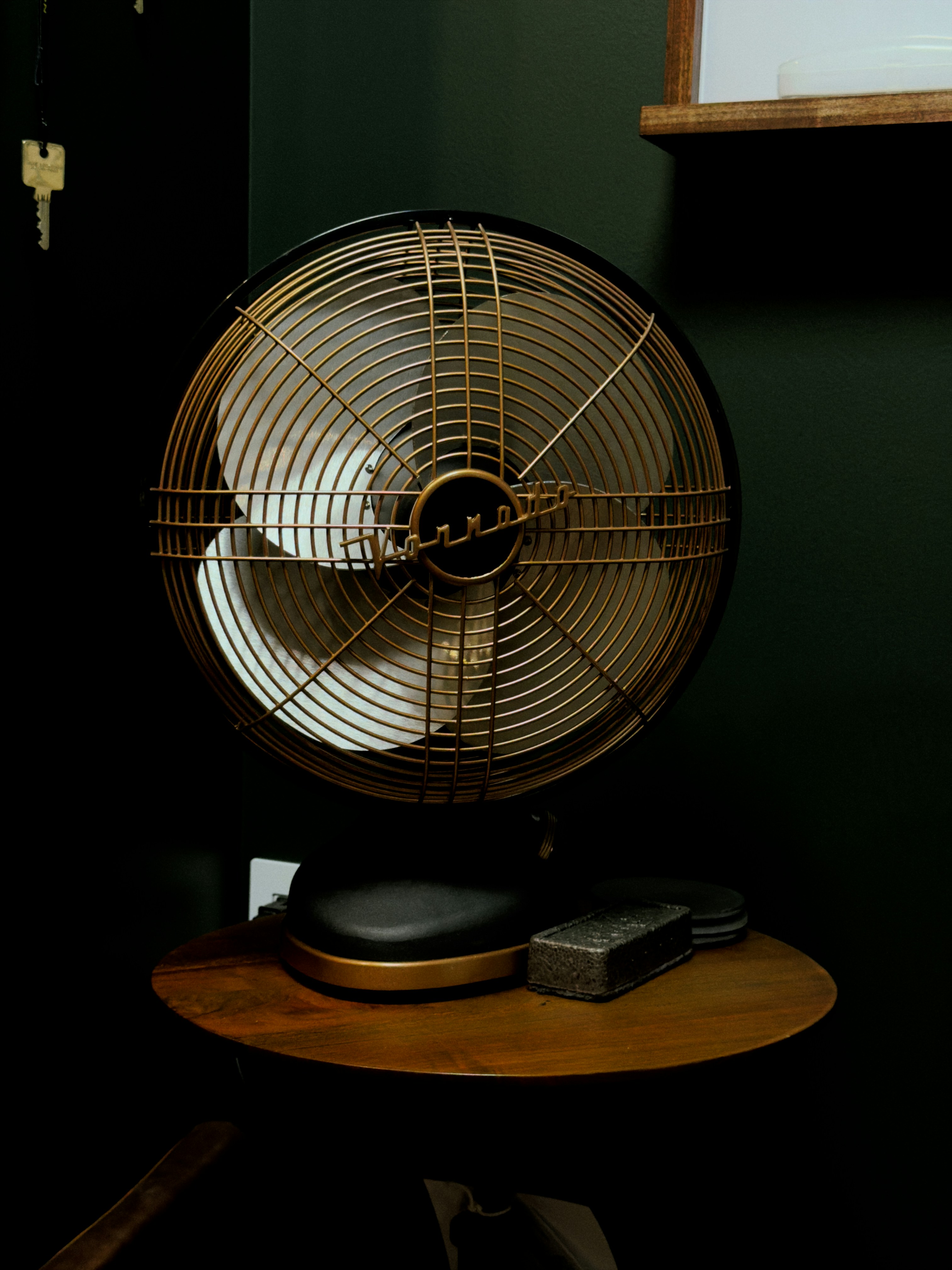 Antique desk fan with brass accents on table.