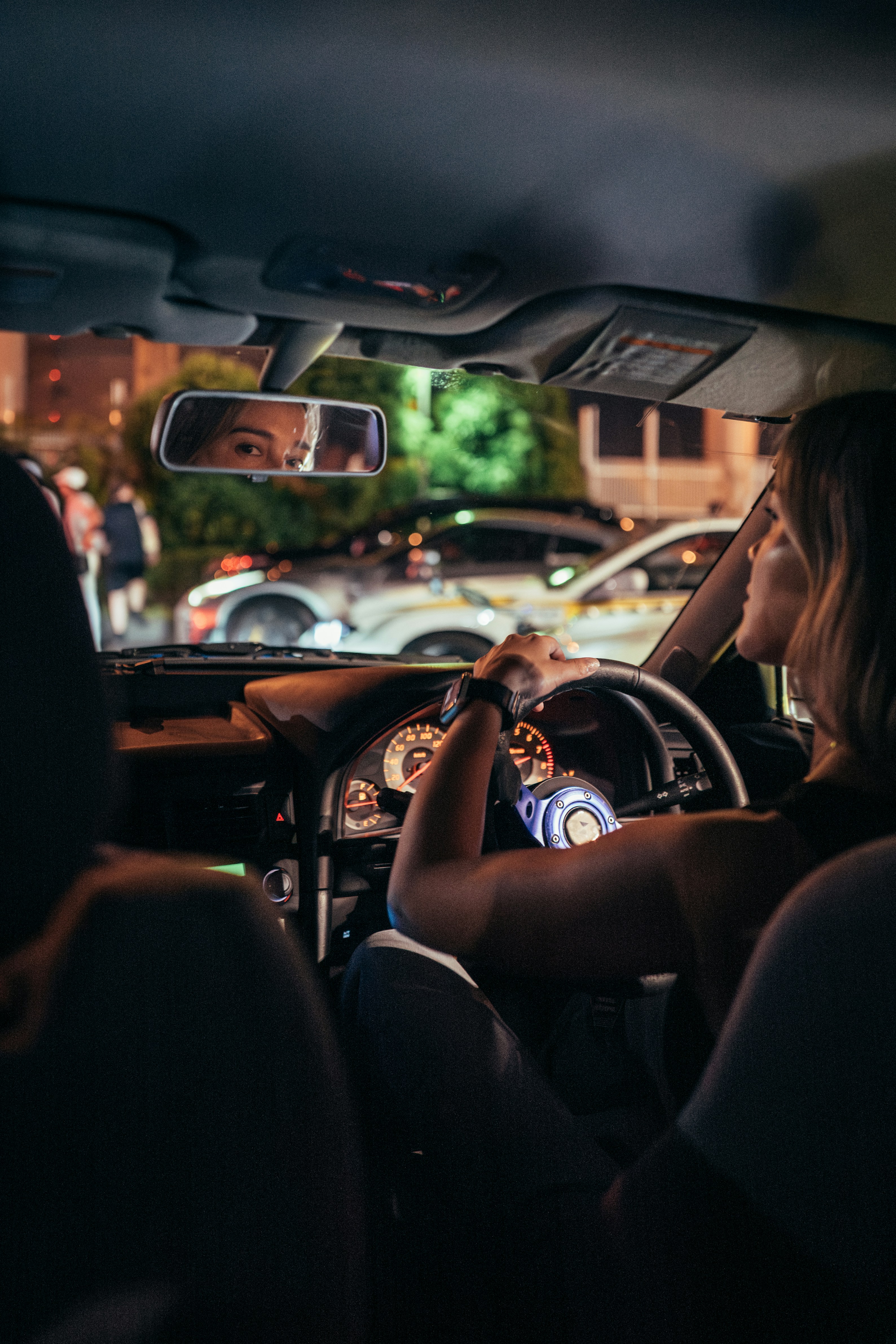 Woman driving car at night with city lights reflection