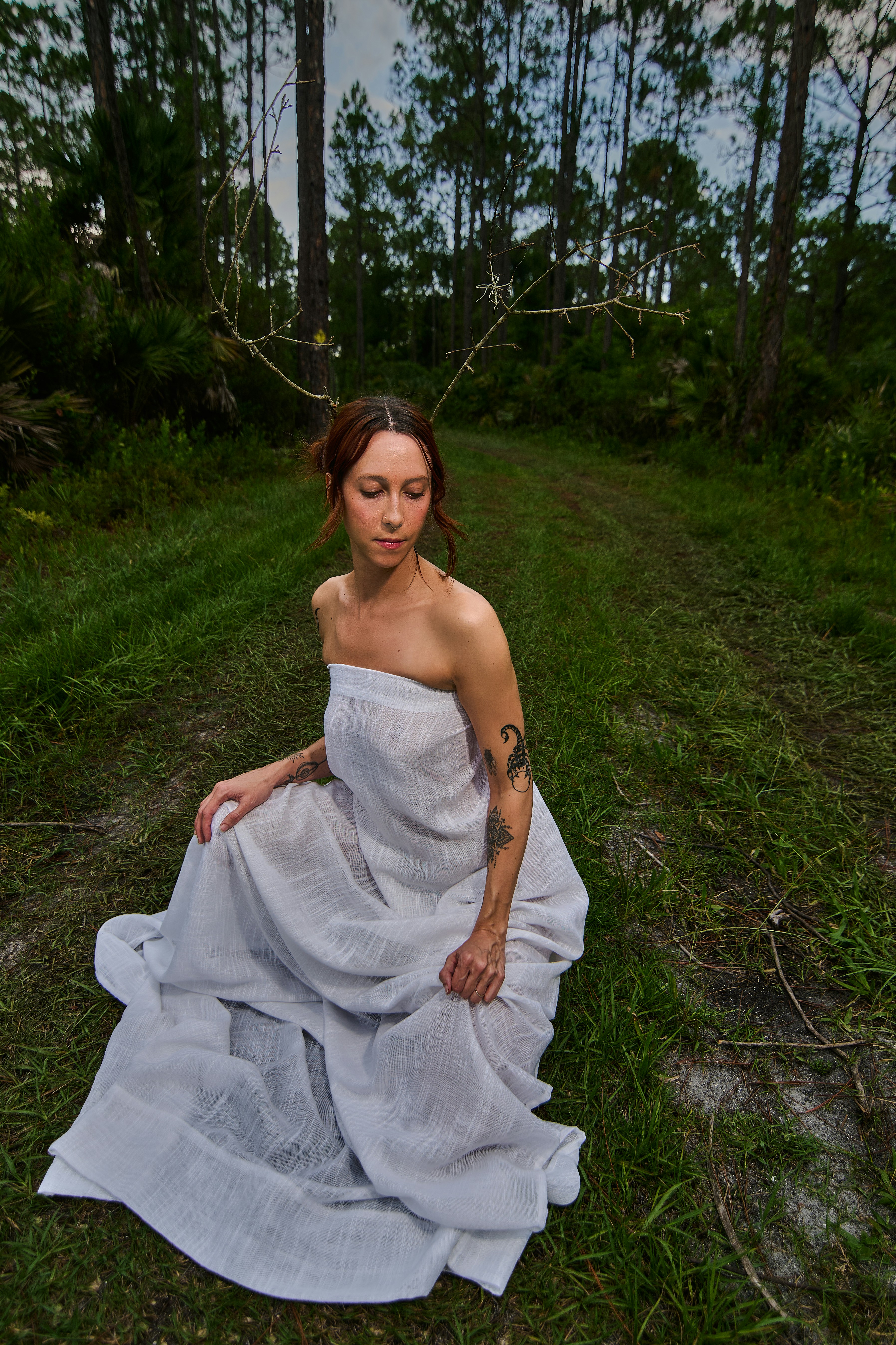 Woman with branches on head in forest
