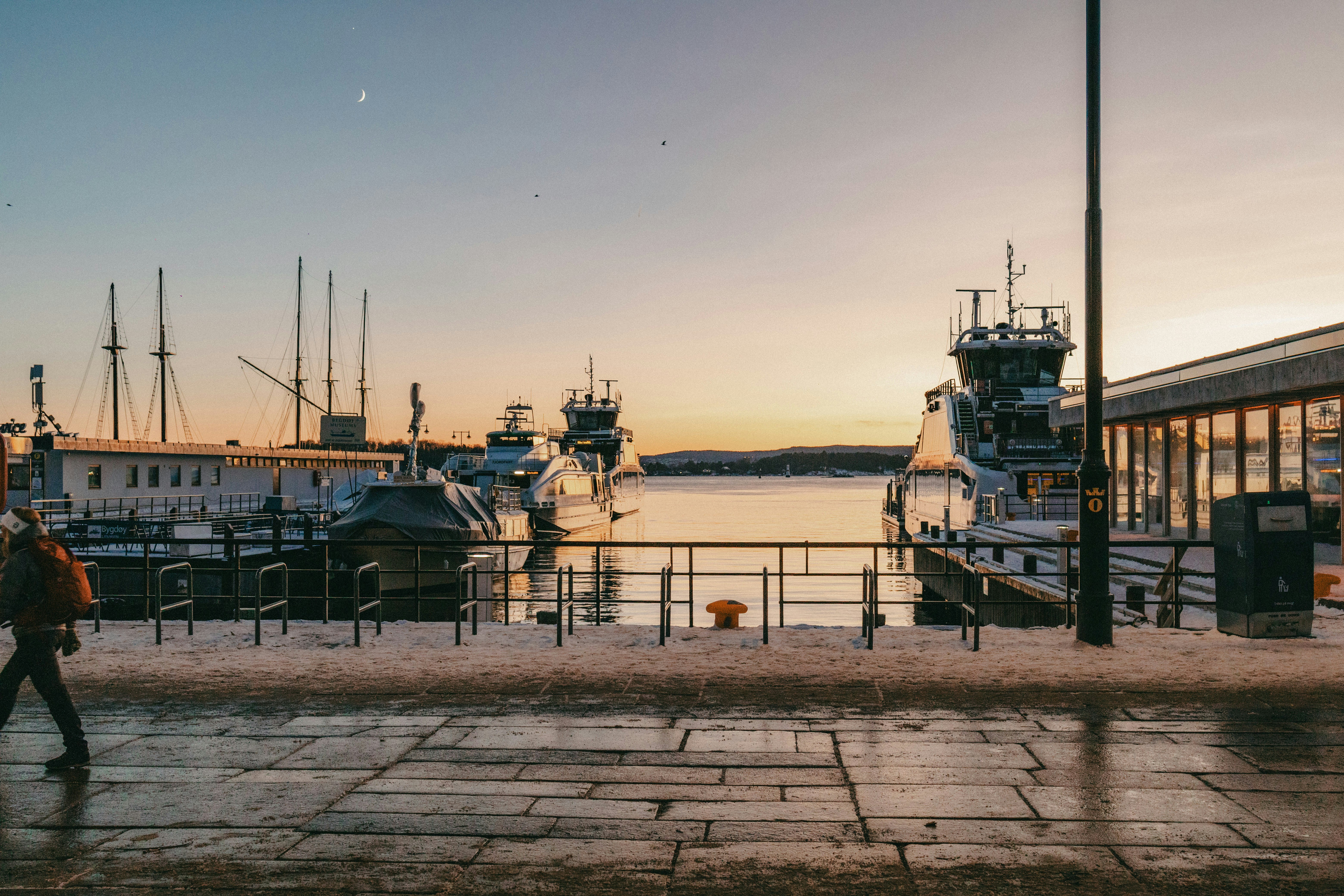 Harbor with boats at sunset with a person walking