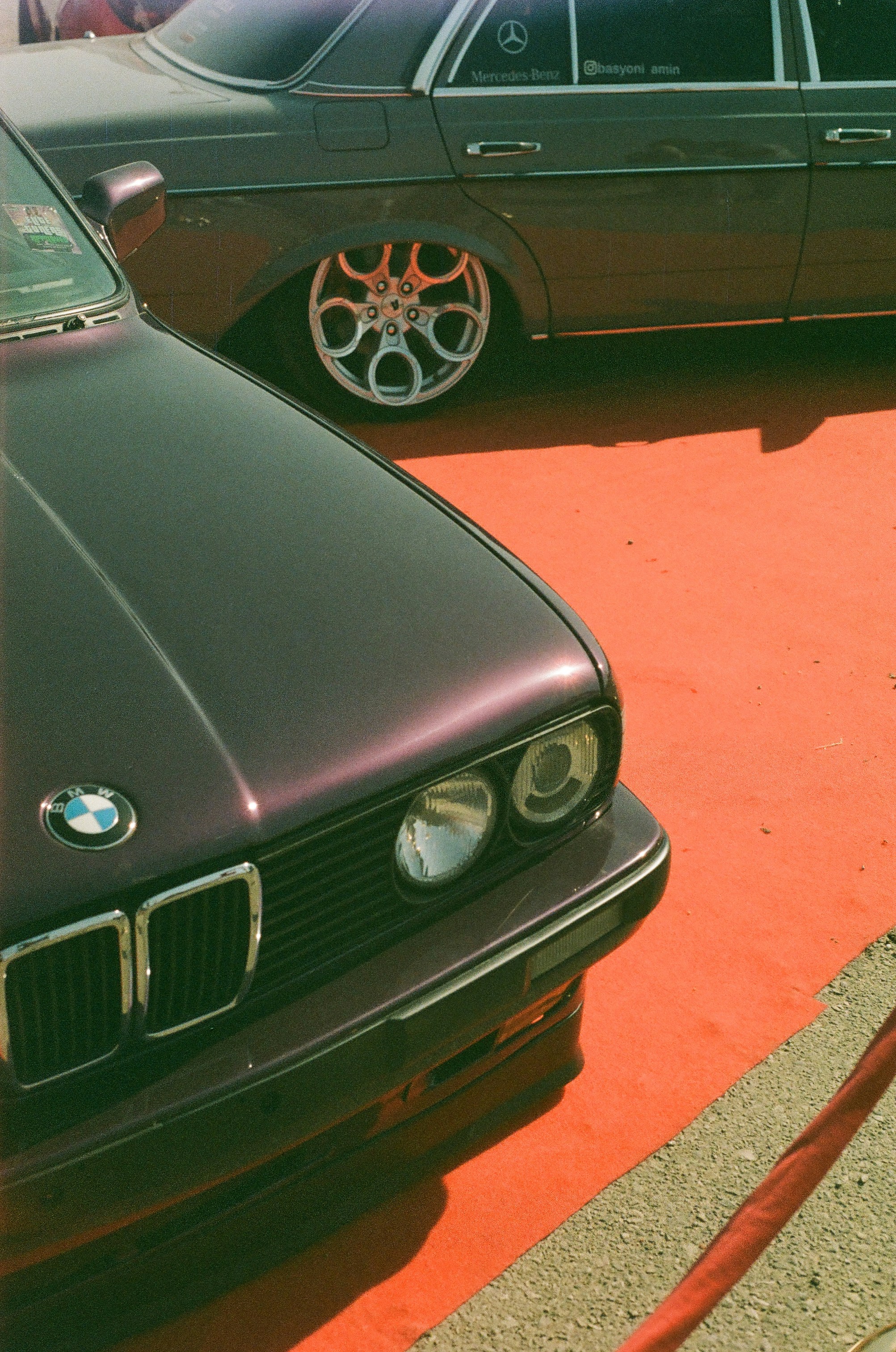 Zwei Oldtimer parken auf einer leuchtend orangefarbenen Fläche