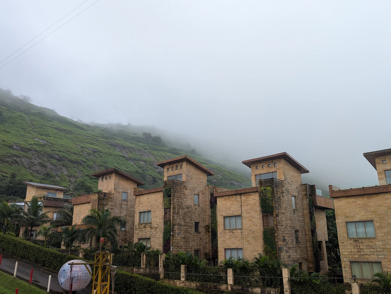 Resort buildings set against a misty green hillside