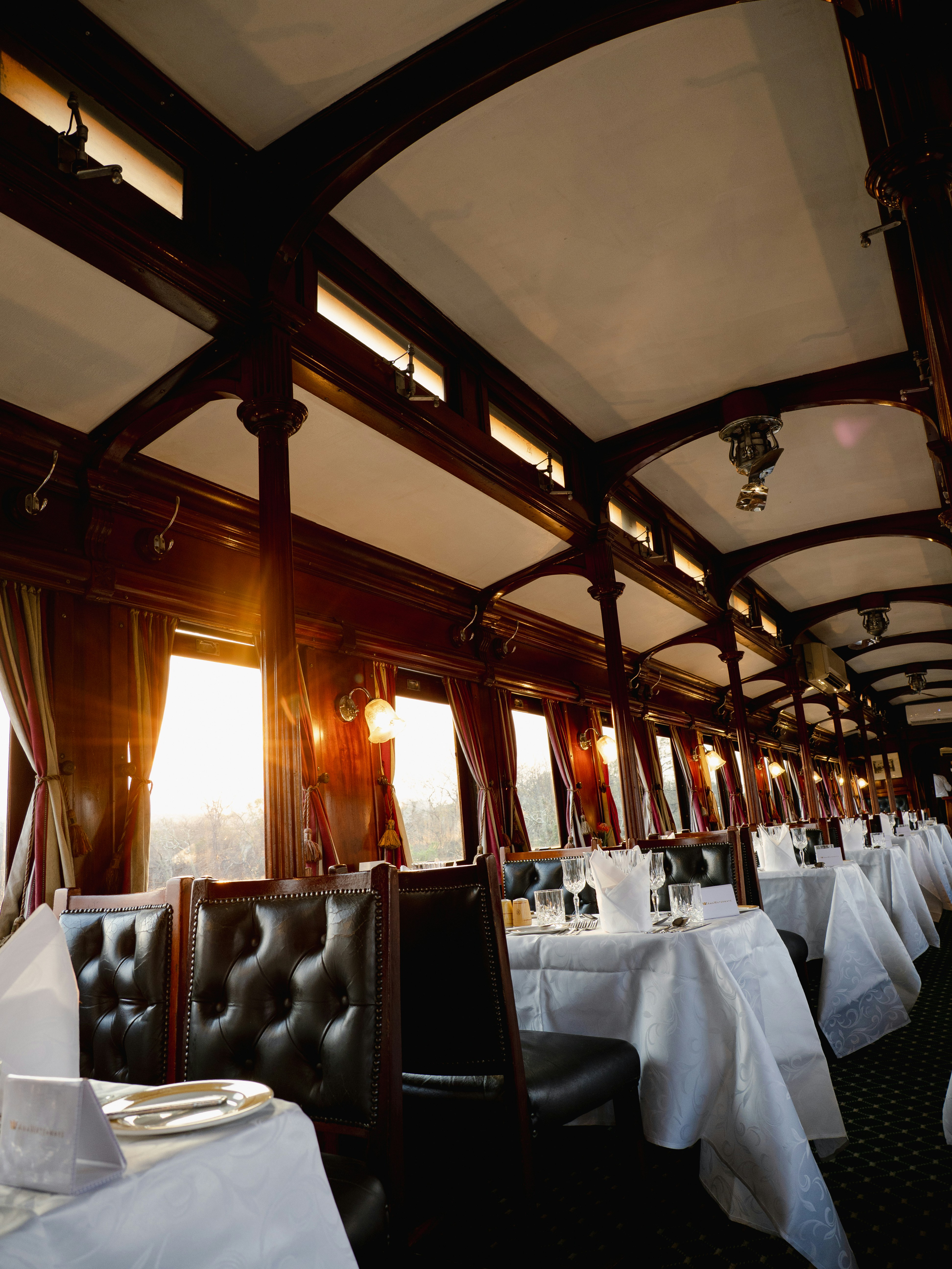 Elegant dining car interior with tables set for dinner.