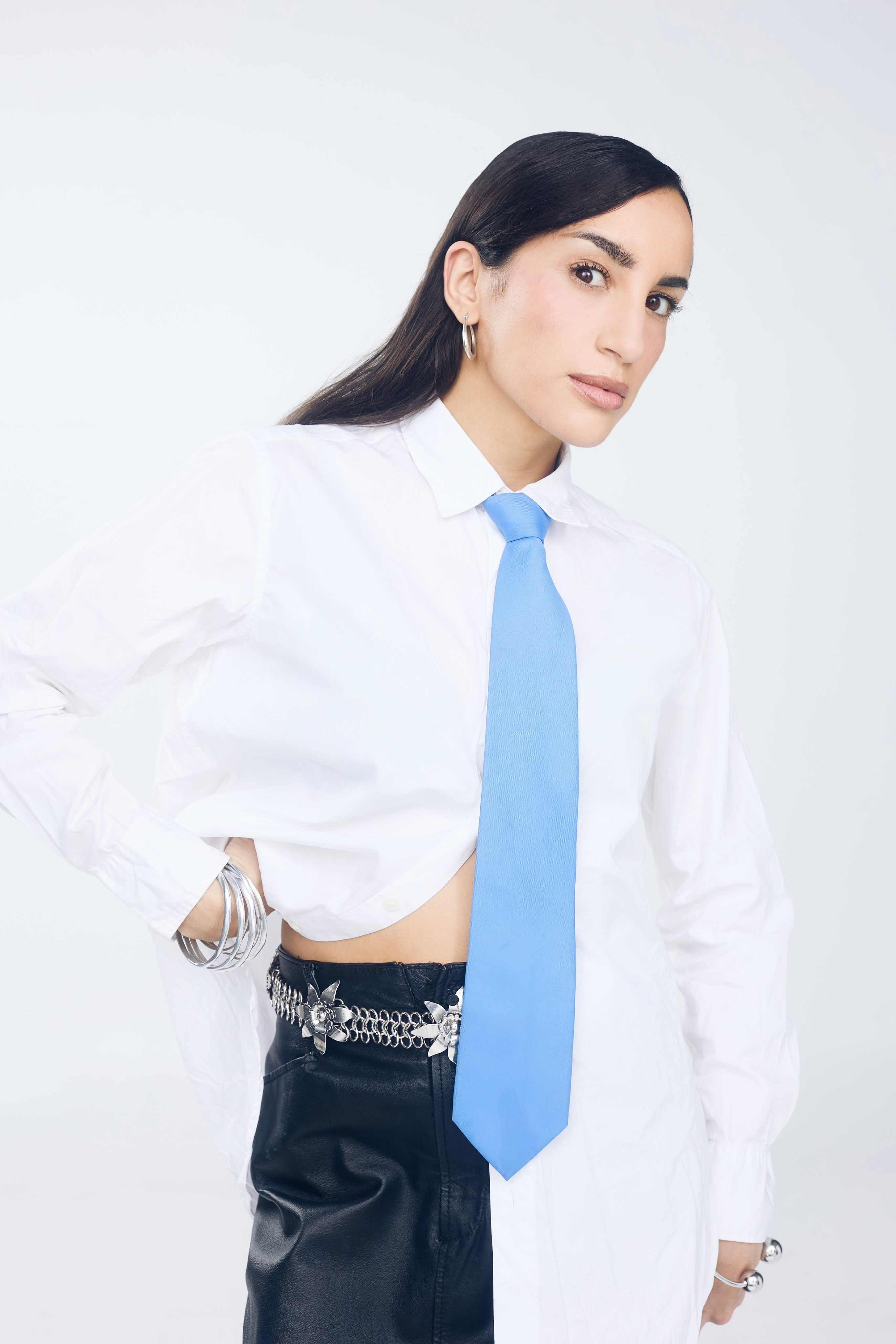 Woman in white shirt and blue tie with jewelry