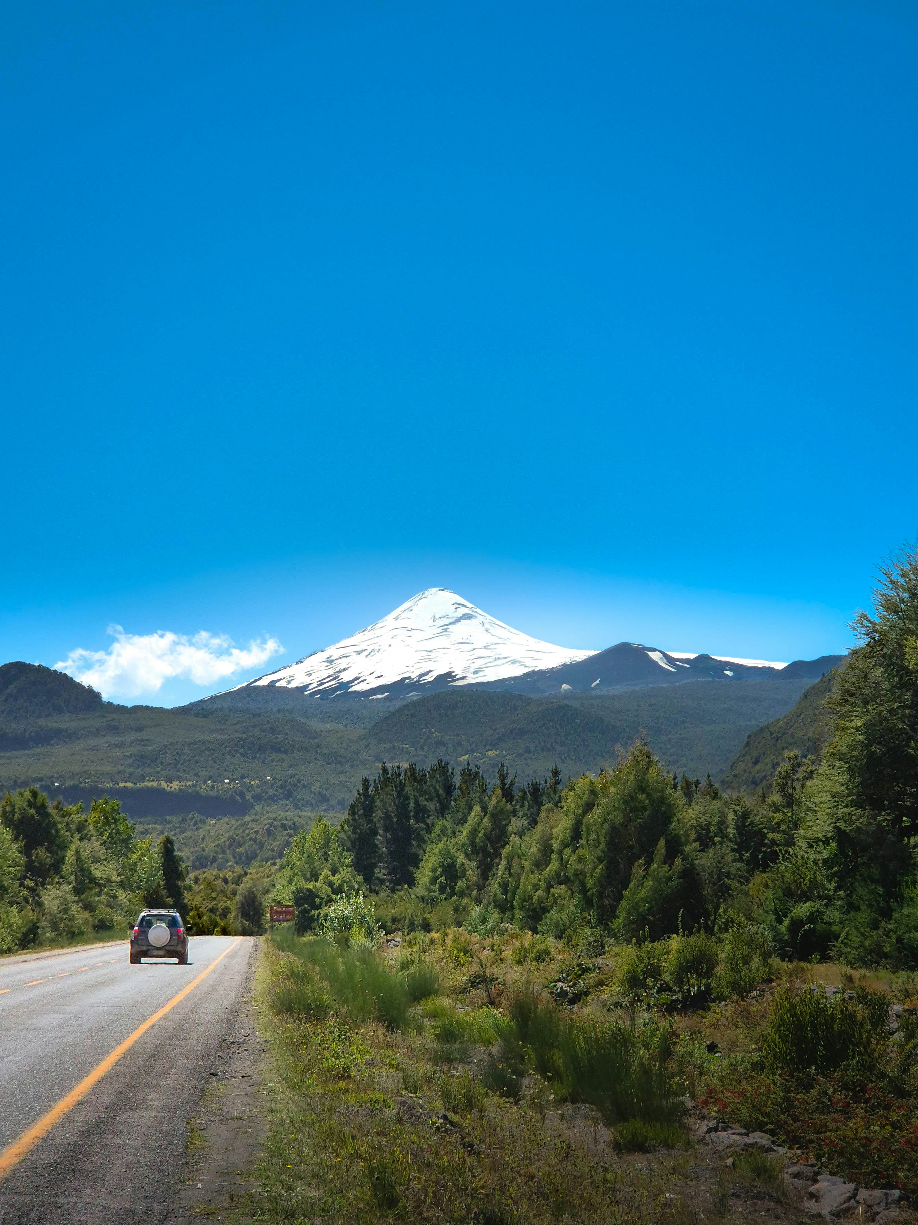 Coche conduciendo por carretera hacia la montaña nevada.