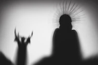 Silhouettes of two figures with dramatic headdresses