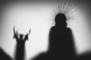 Silhouettes of two figures with dramatic headdresses