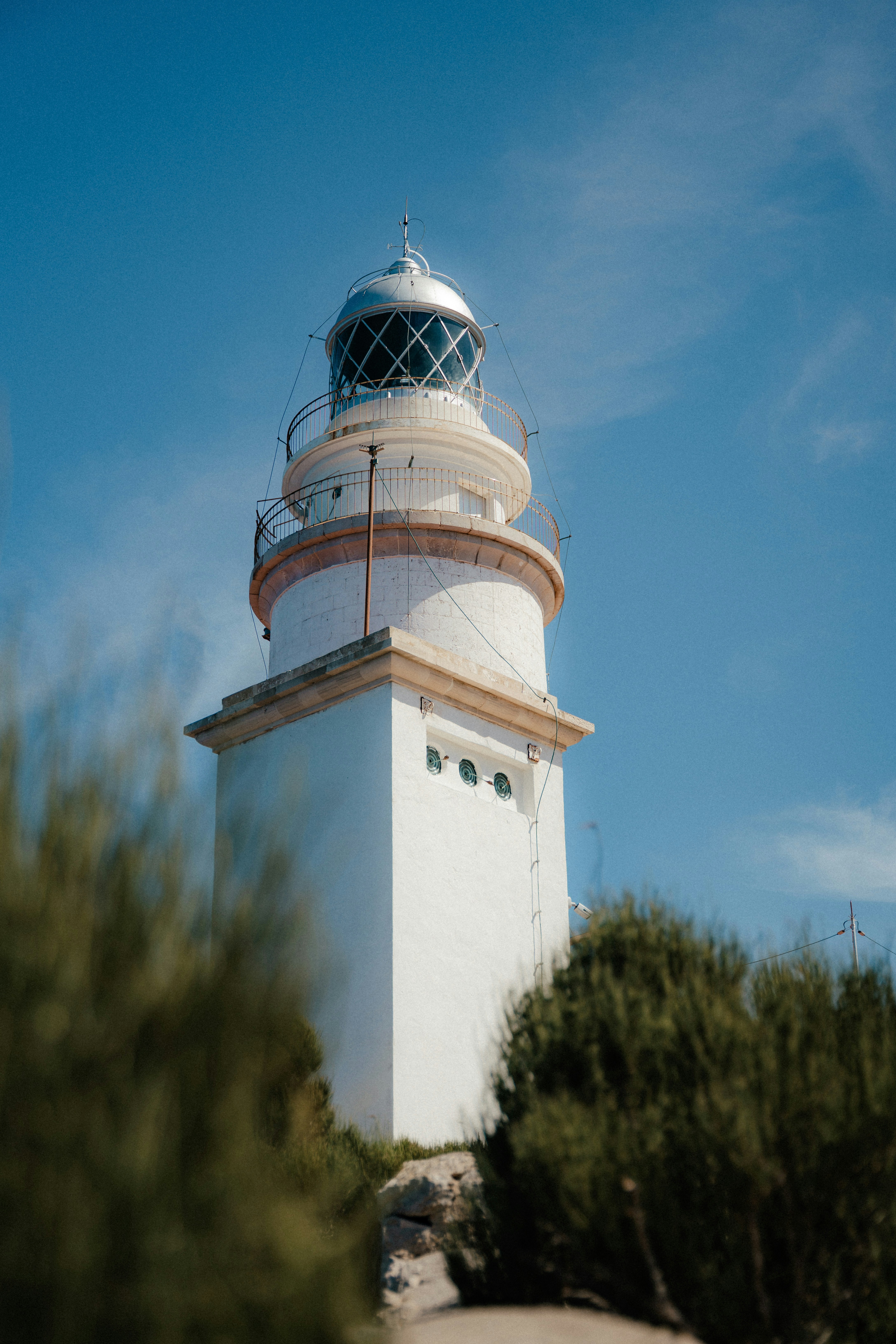 White lighthouse on a rocky coast under blue sky