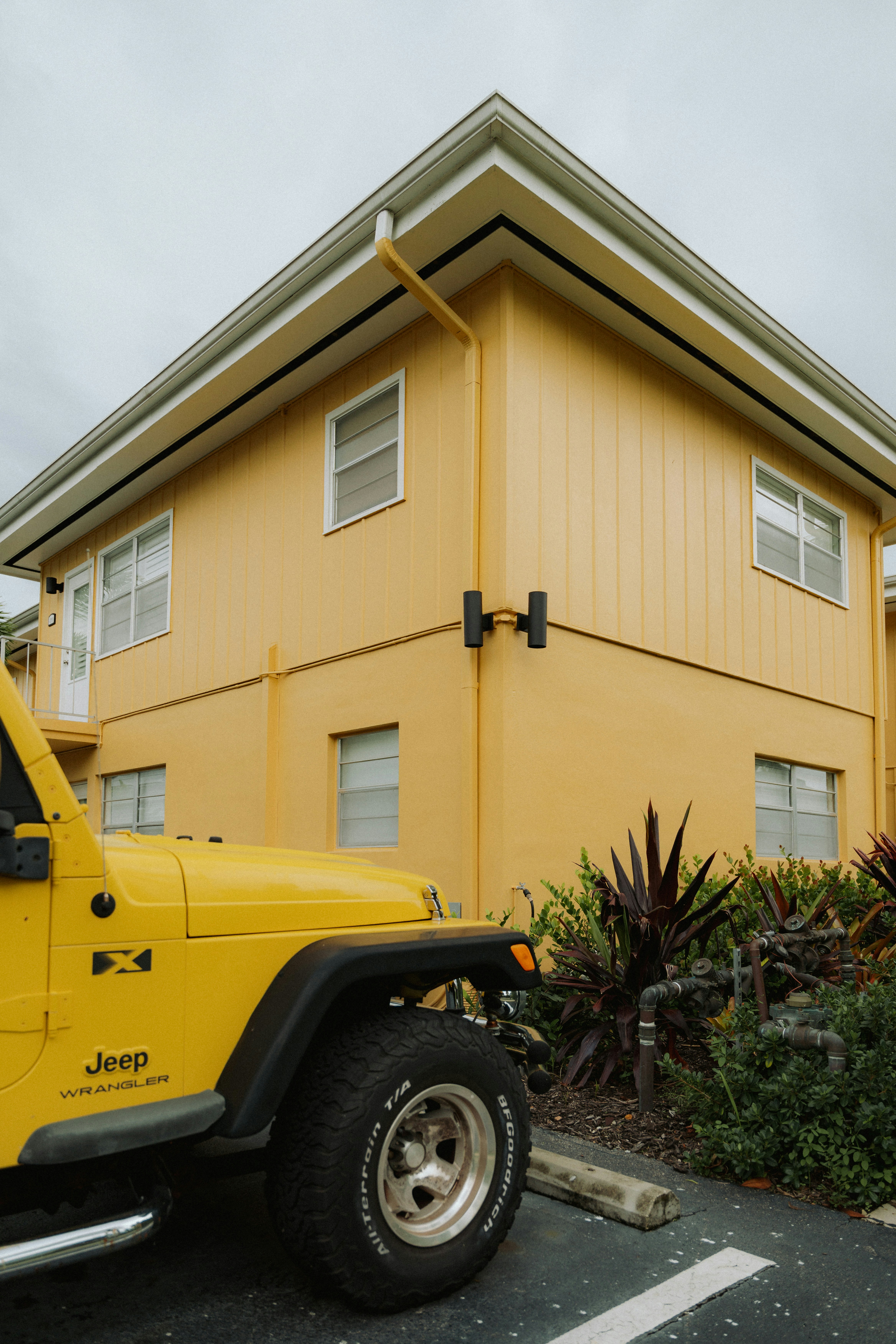 Yellow jeep parked next to a yellow building.