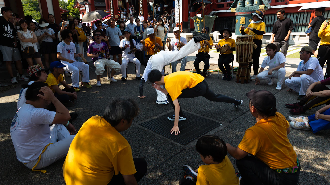 People gathered in a circle watching two capoeiristas play