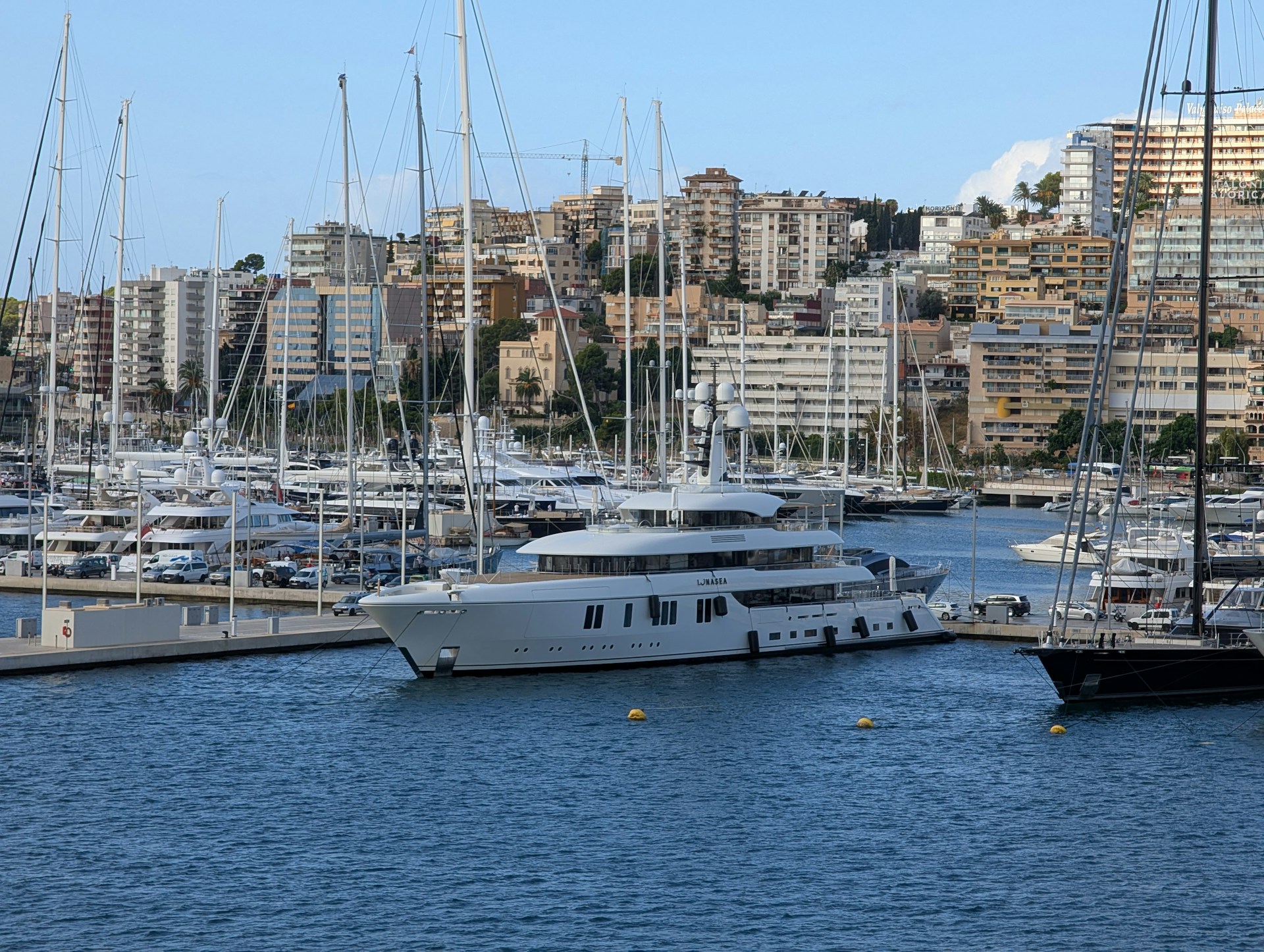 Large white yacht docked in a busy harbor.