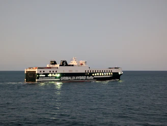 A large ferry sails on the ocean at dusk.