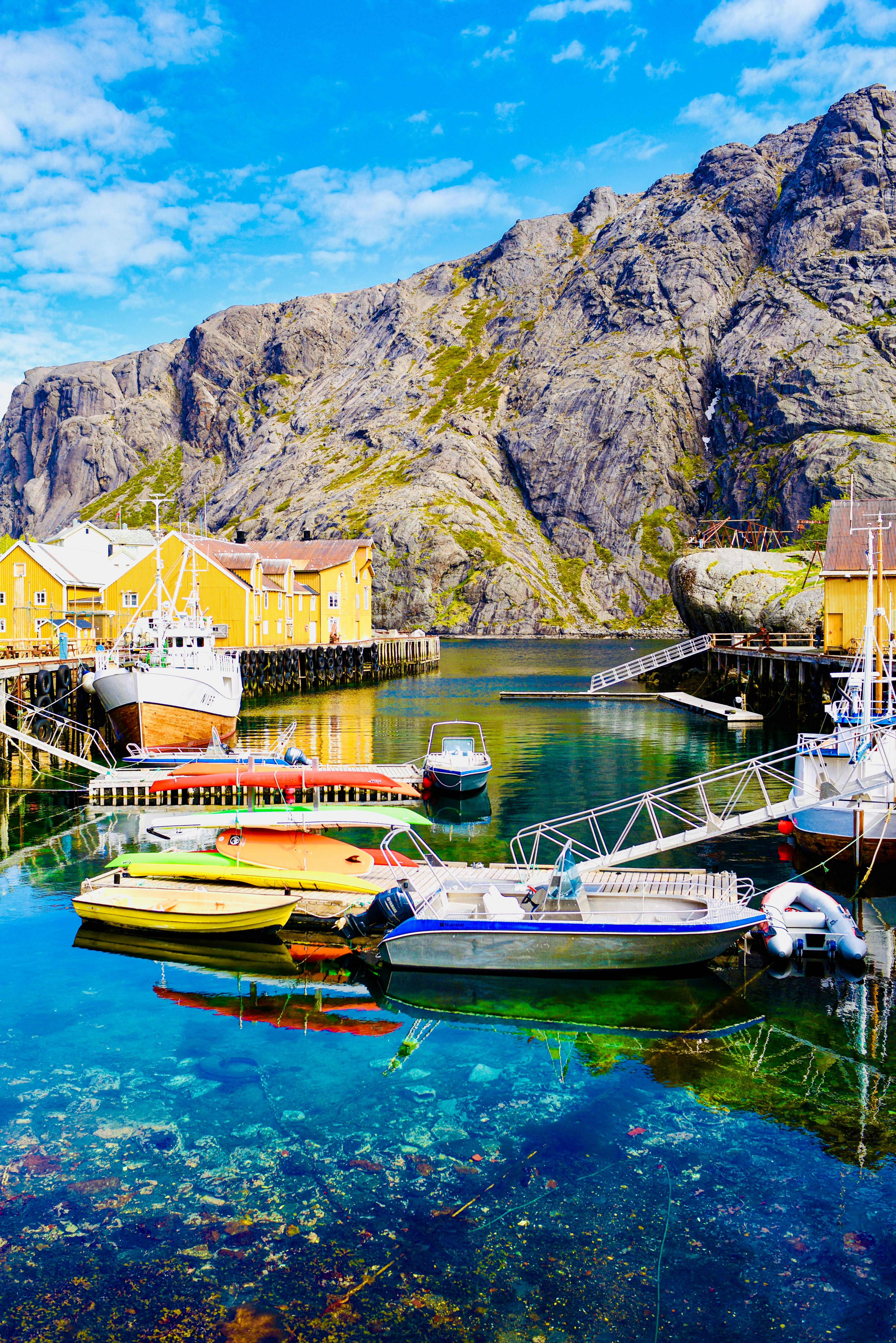 Buntes Fischerdorf mit Booten, die im klaren Wasser angedockt sind.