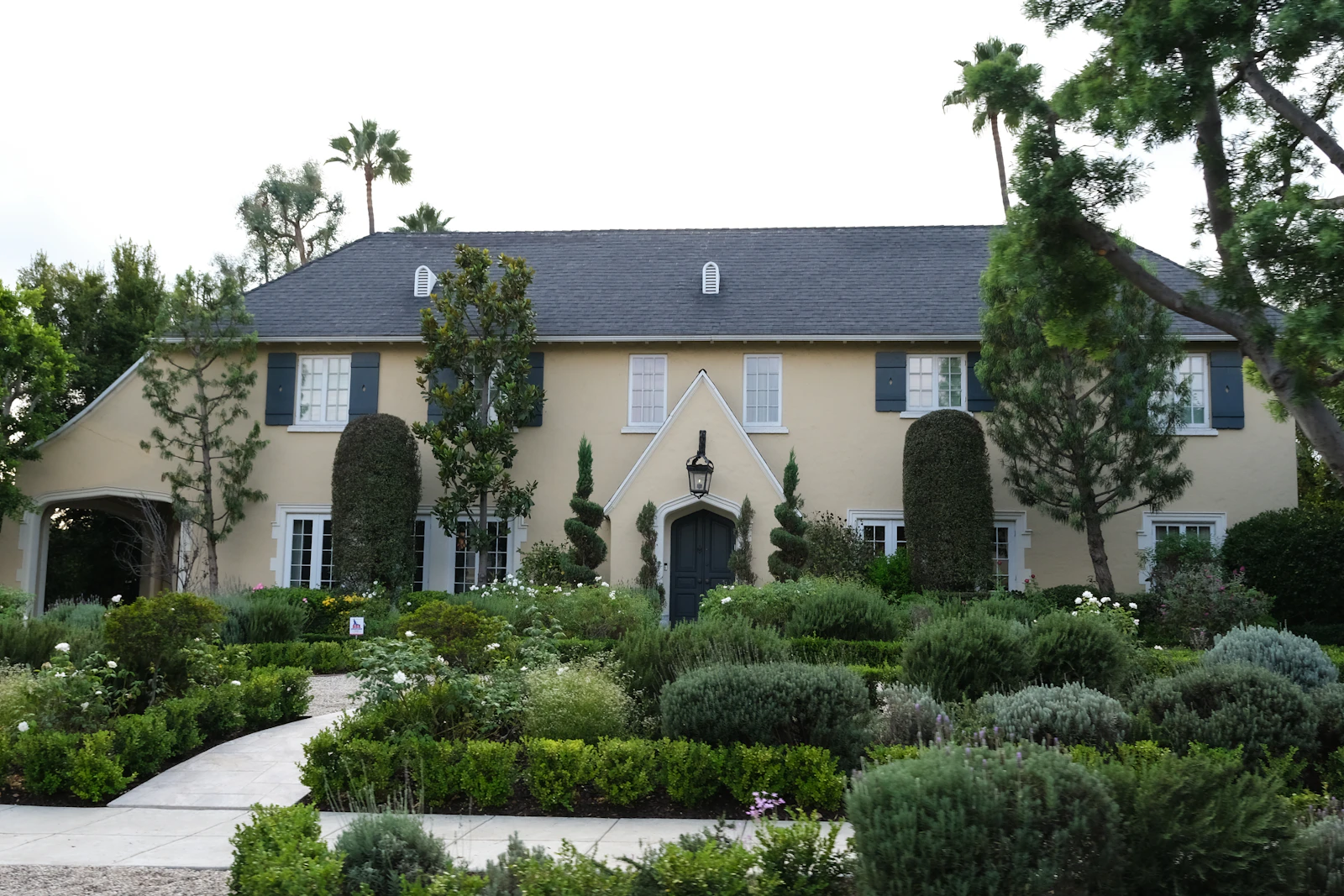 A large home framed by manicured garden beds and mature plantings