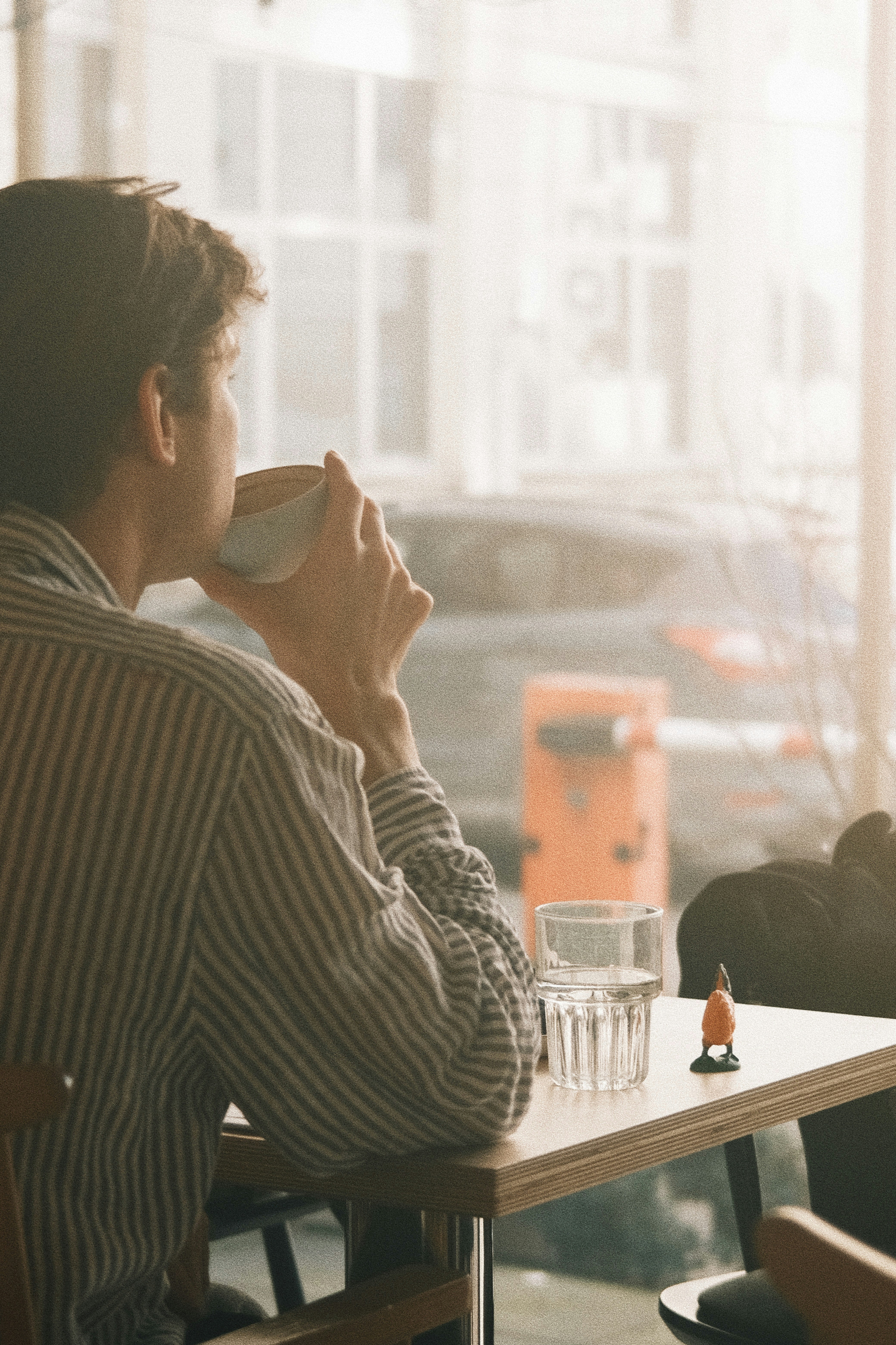 Man drinking coffee at a table by the window