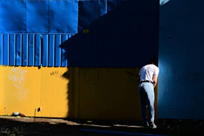 Man stands against a blue and yellow wall.