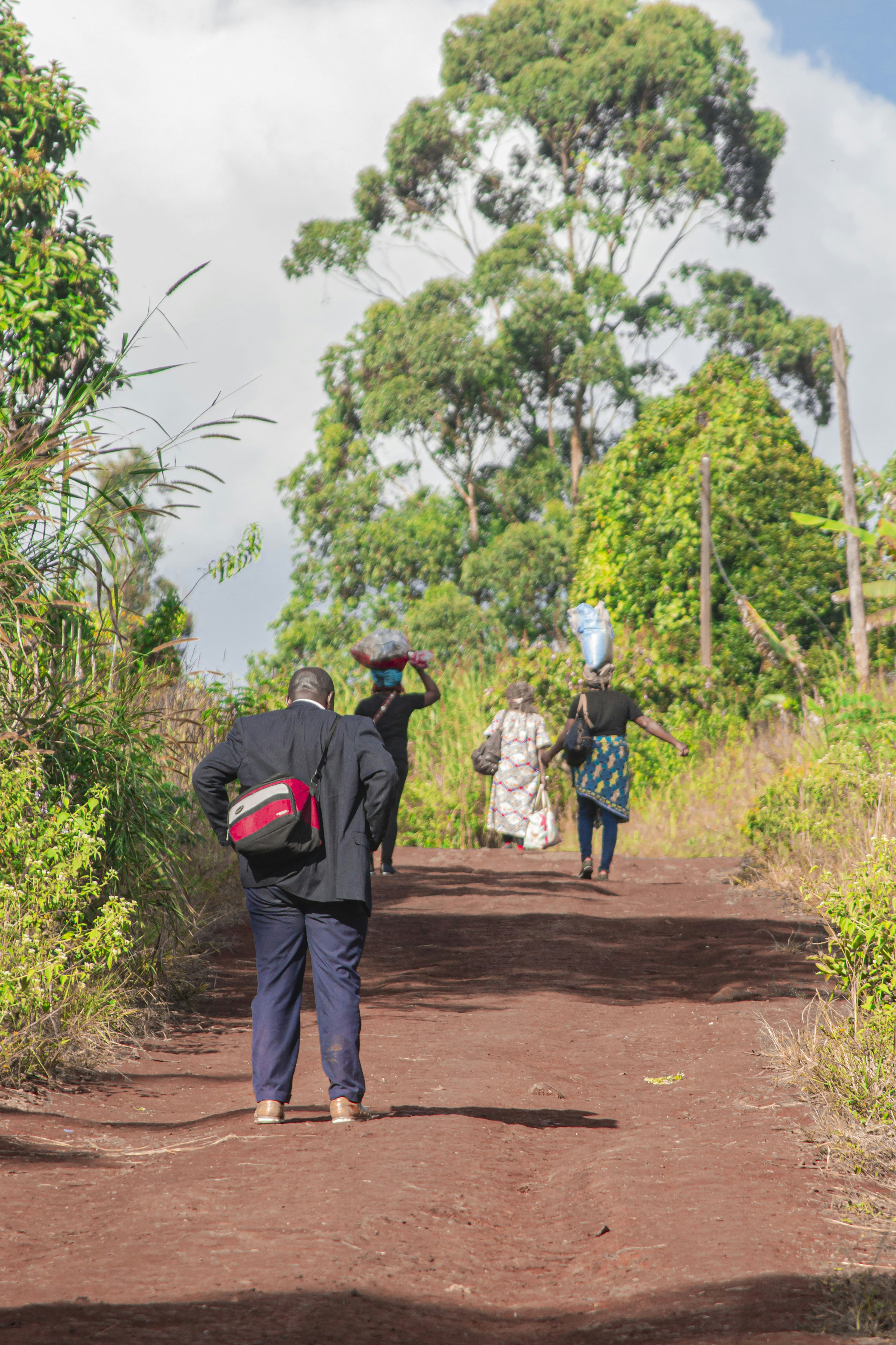 Personas cargando cestas en un camino de tierra
