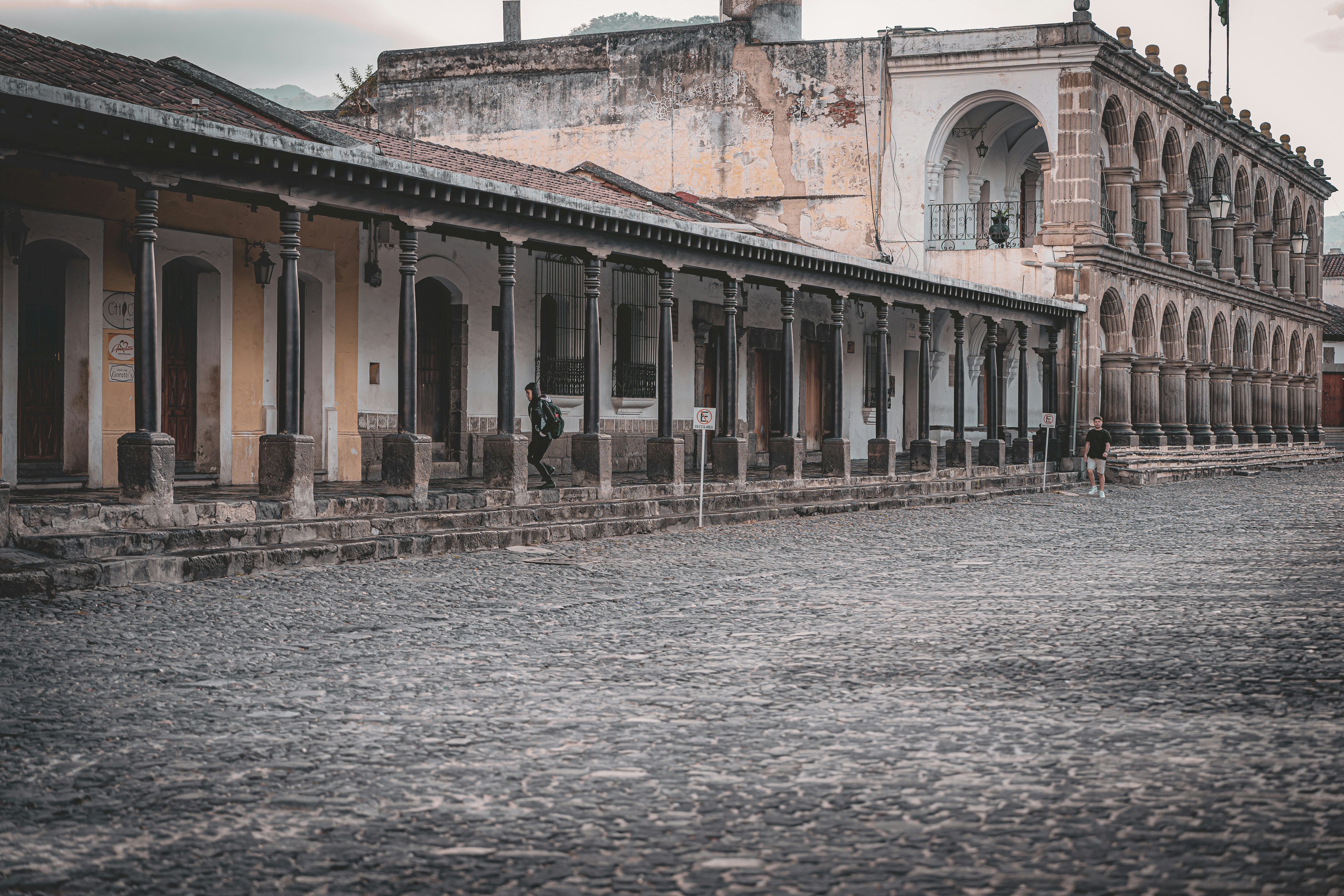 Colonial building with arched windows and cobblestone courtyard