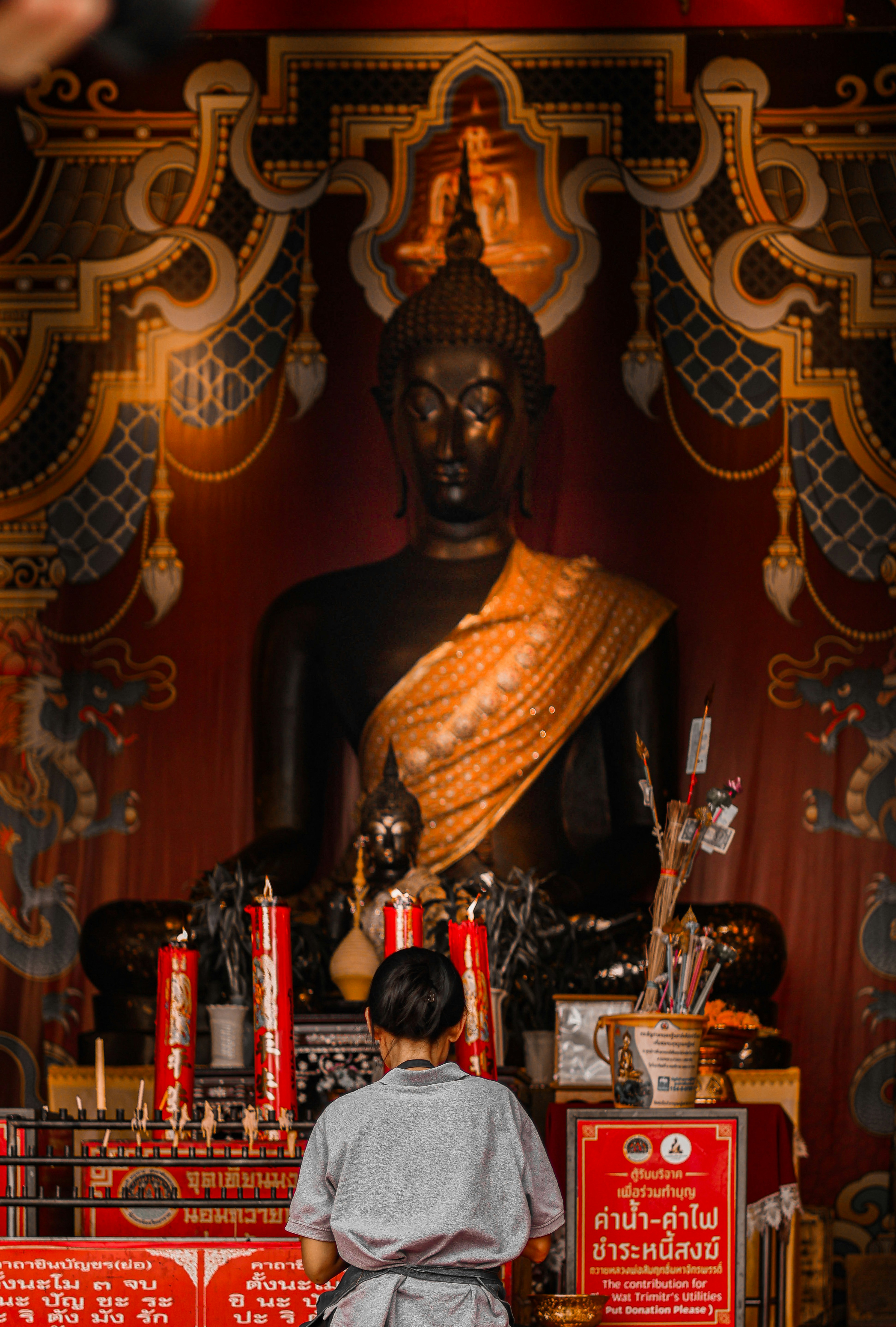Person praying before a large buddha statue.