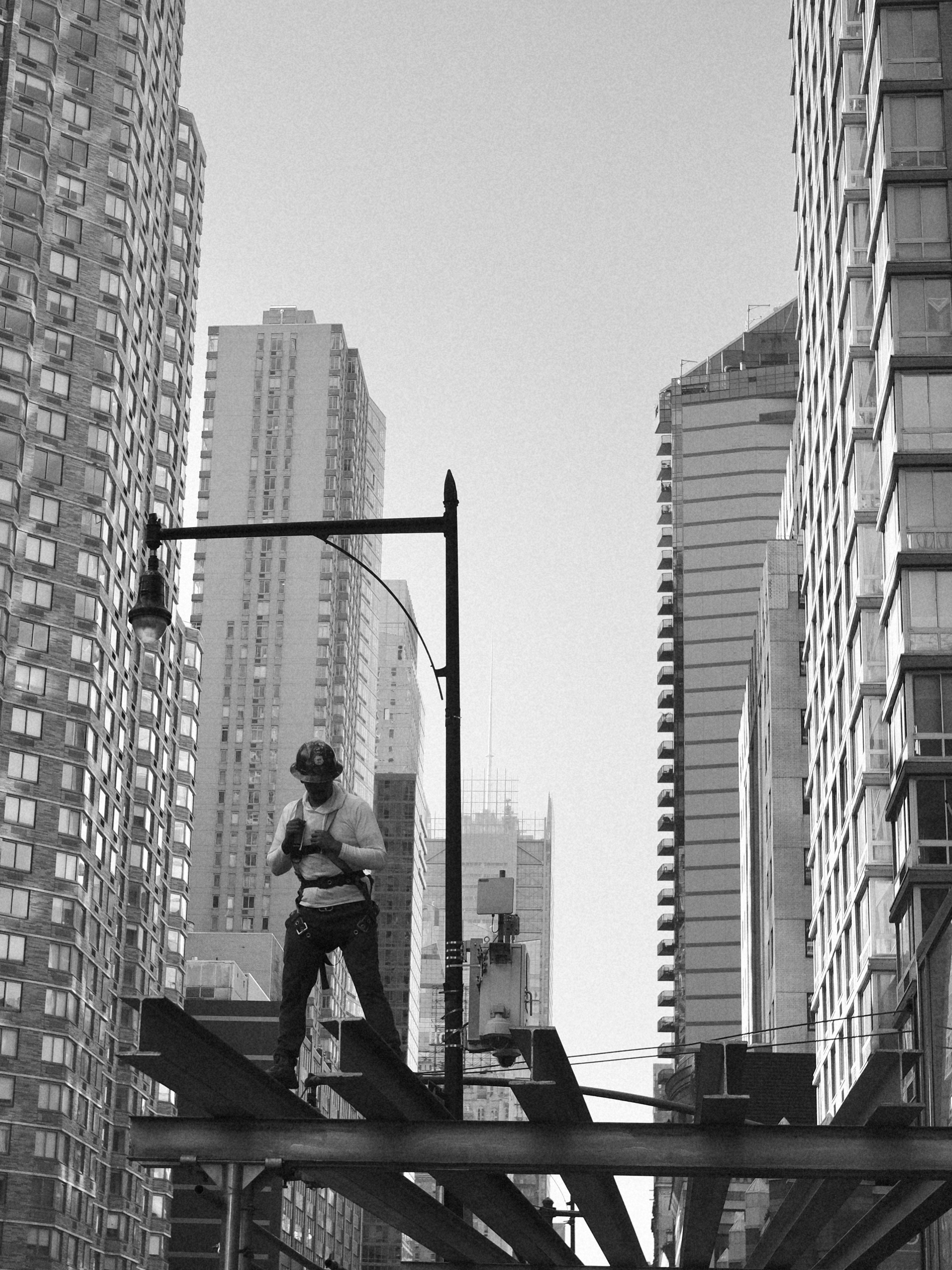 Construction worker on steel beams between city buildings