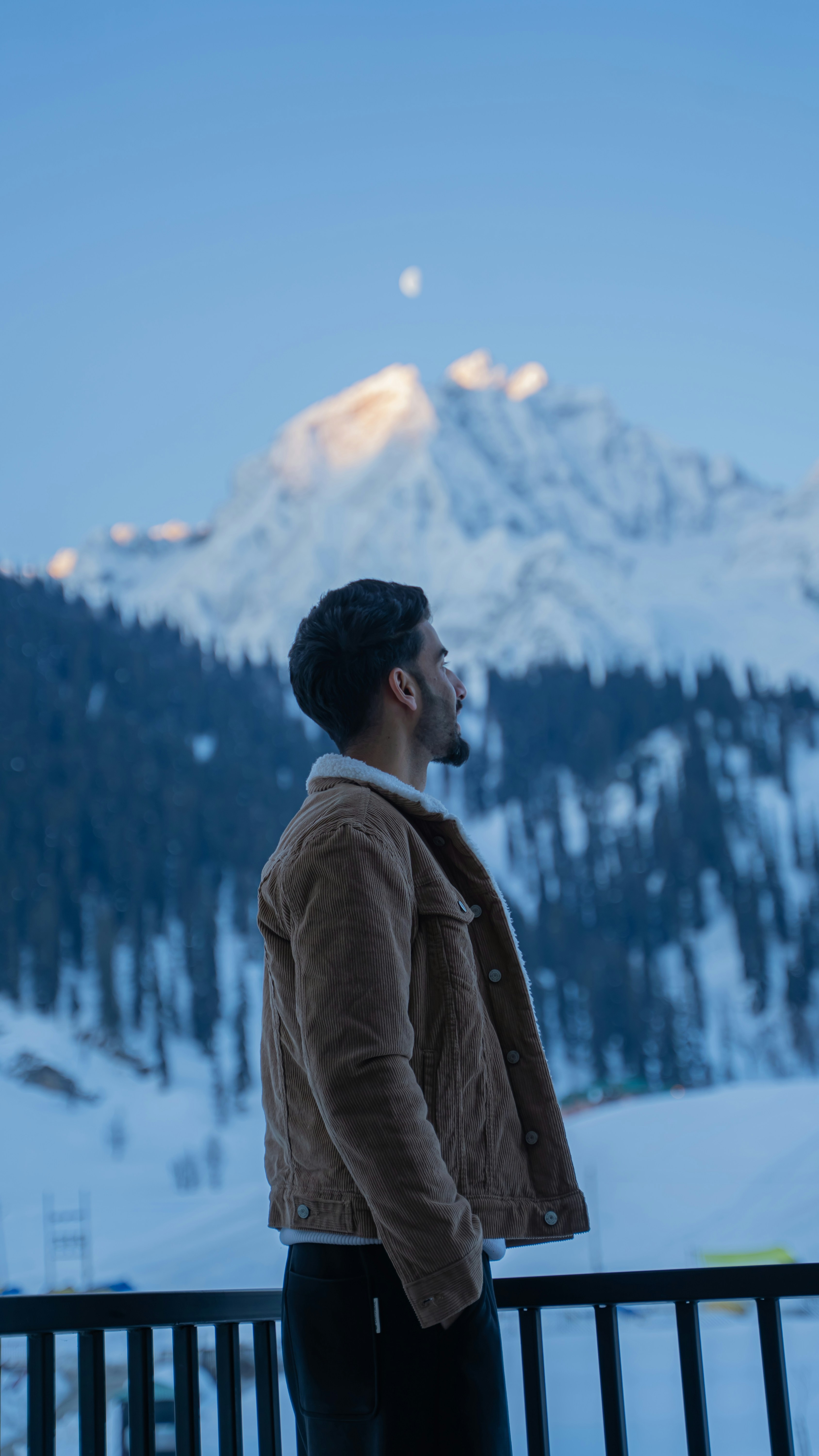 Man looking at snow-capped mountains under a clear sky