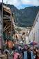People walking down a colorful street with mountains behind.