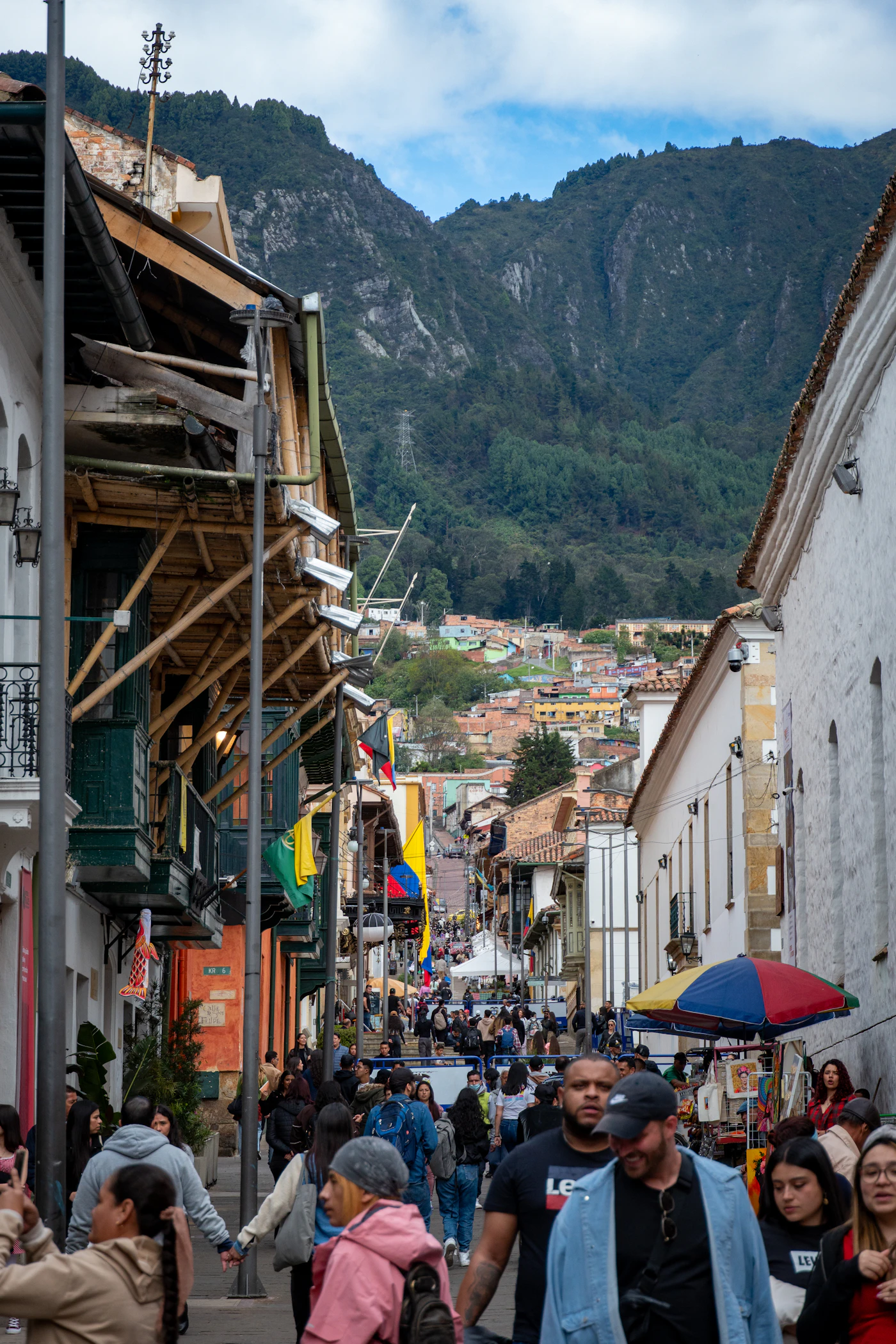 People walking down a colorful street with mountains behind