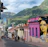 Colorful street art adorns buildings in a hilly city neighborhood.