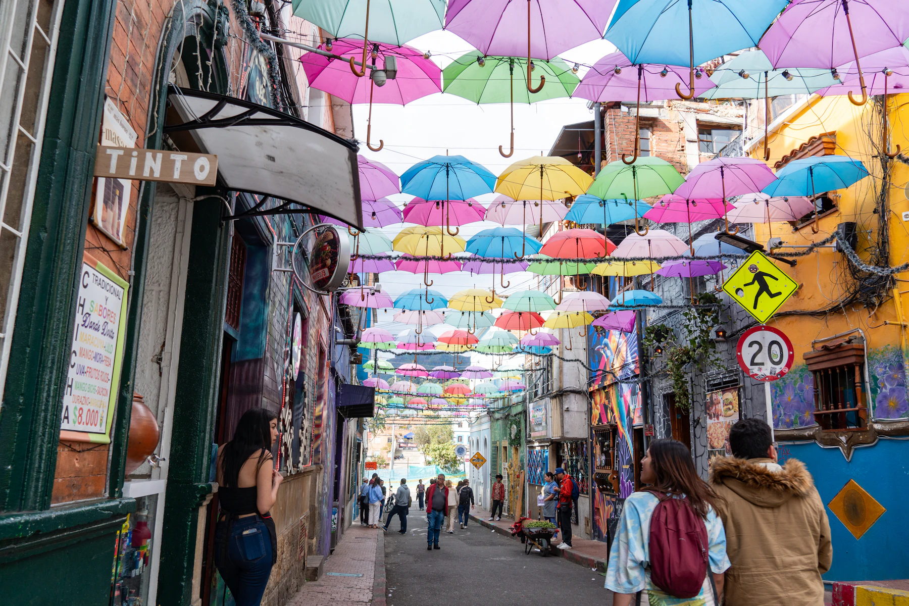 Calle de Bogotá con sombrillas de colores suspendidas y personas caminando