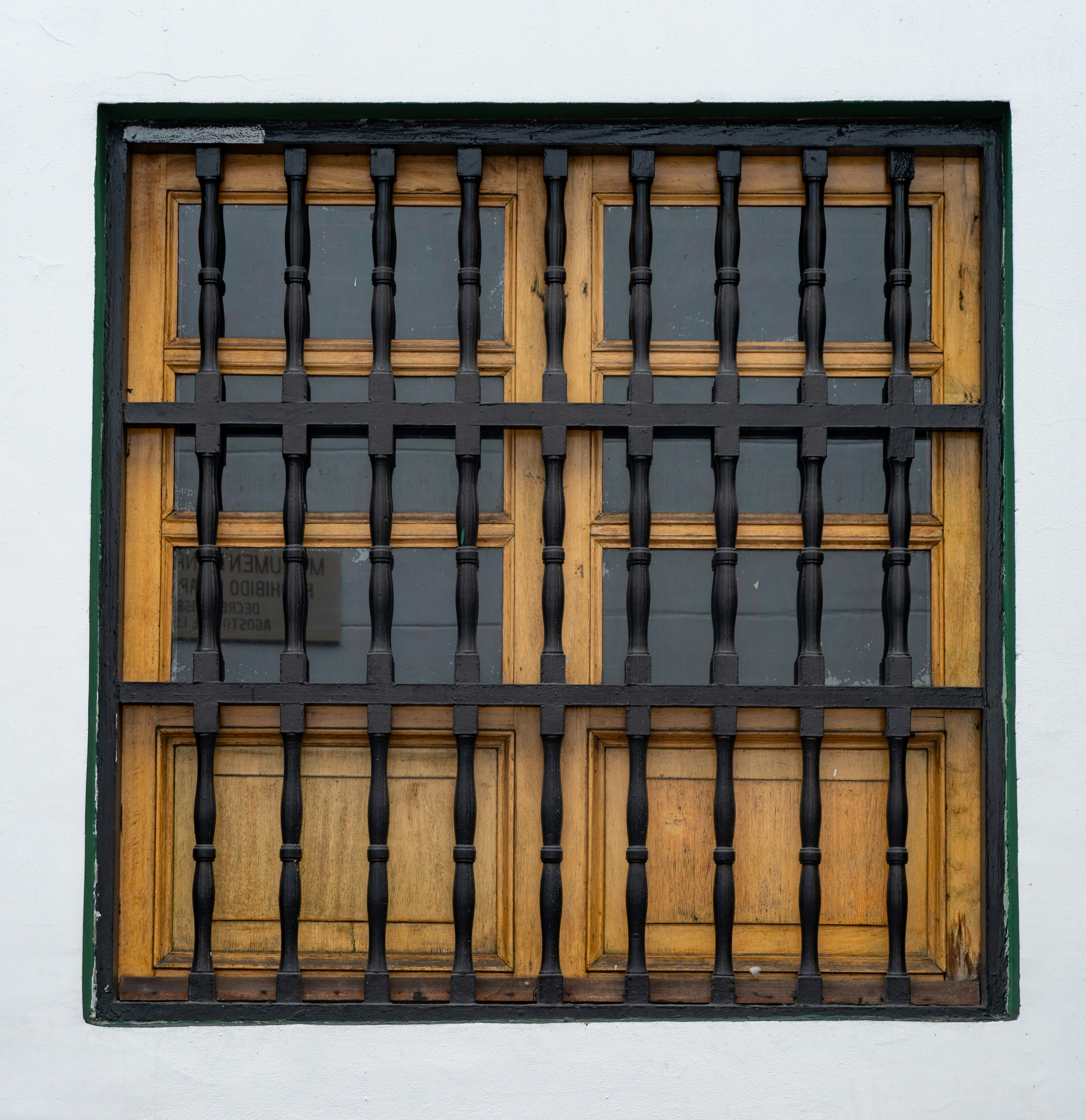 Wooden window with black metal security bars