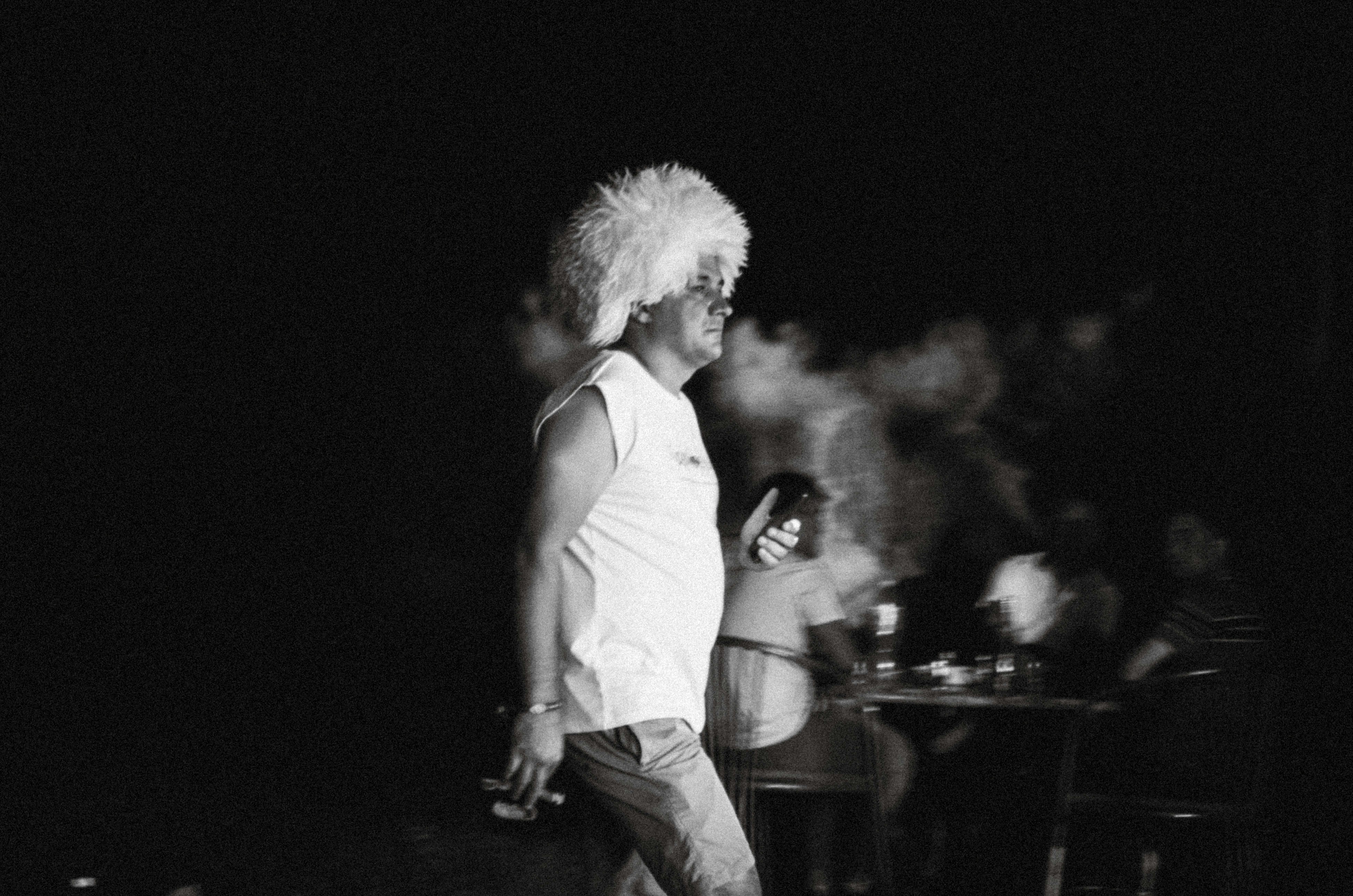 Man with large white wig smoking outdoors at night