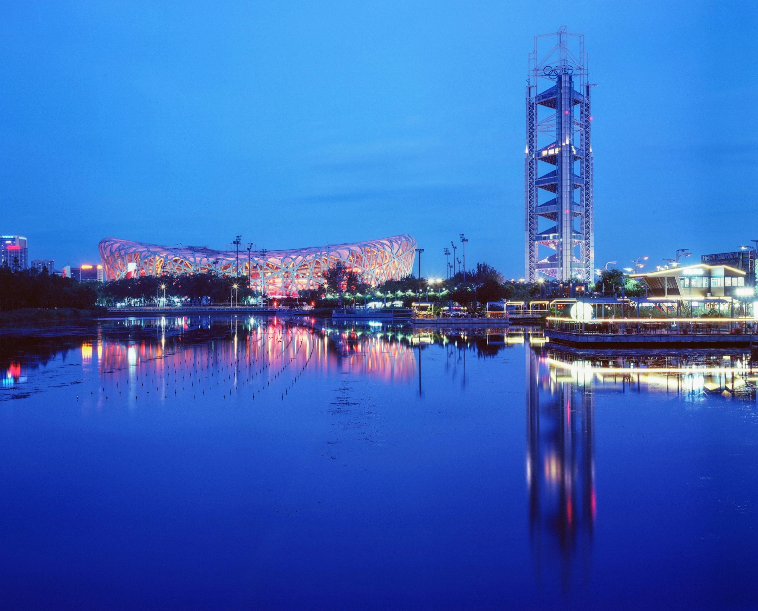 Modern cityscape with illuminated buildings reflected in water.